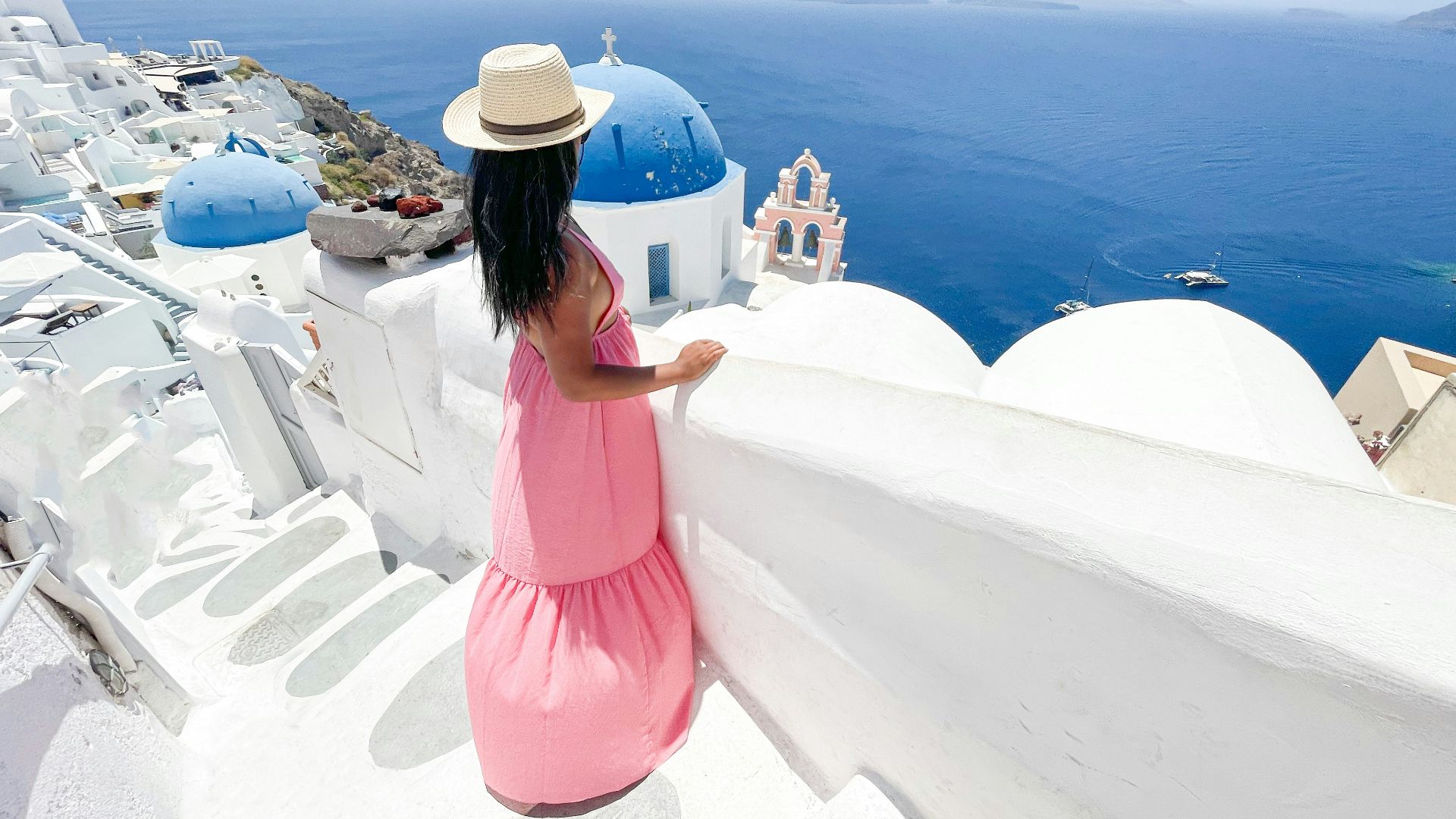 woman in pink dress and white hat standing on white concrete surface during daytime