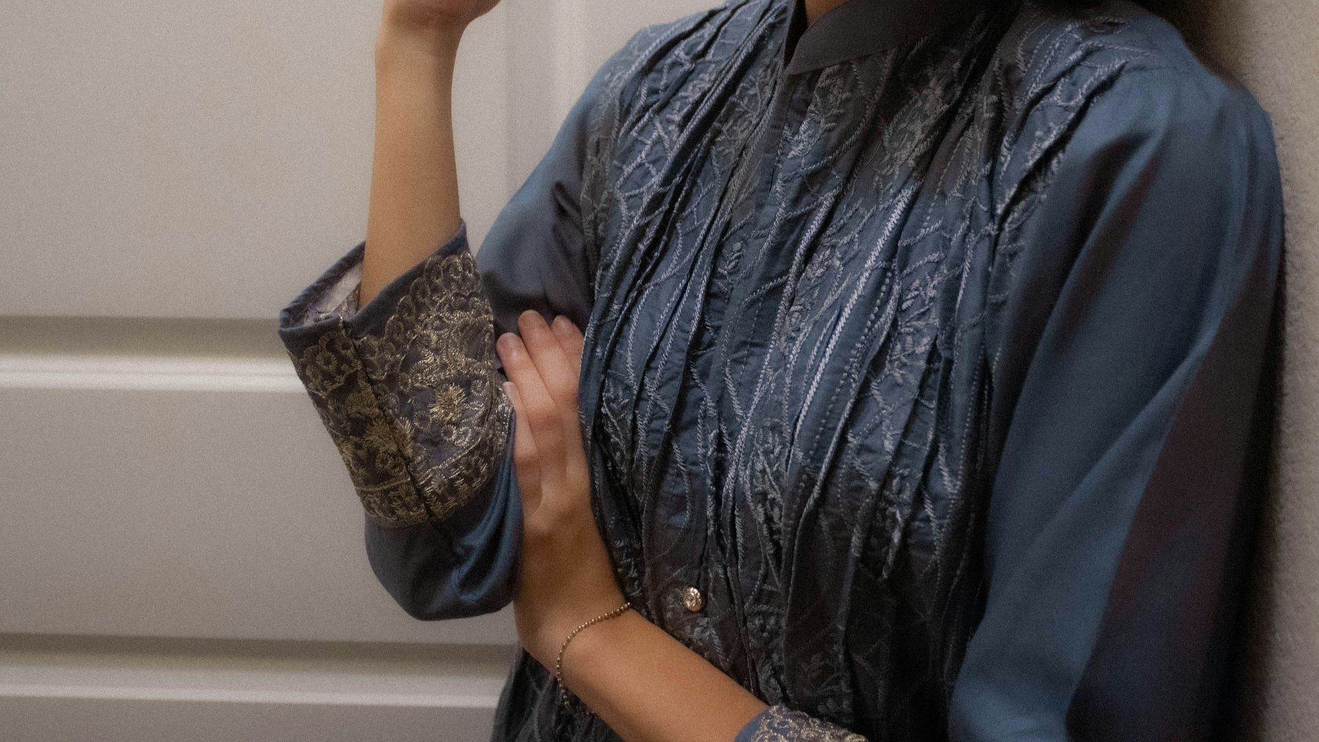 A woman standing next to a wall holding an umbrella