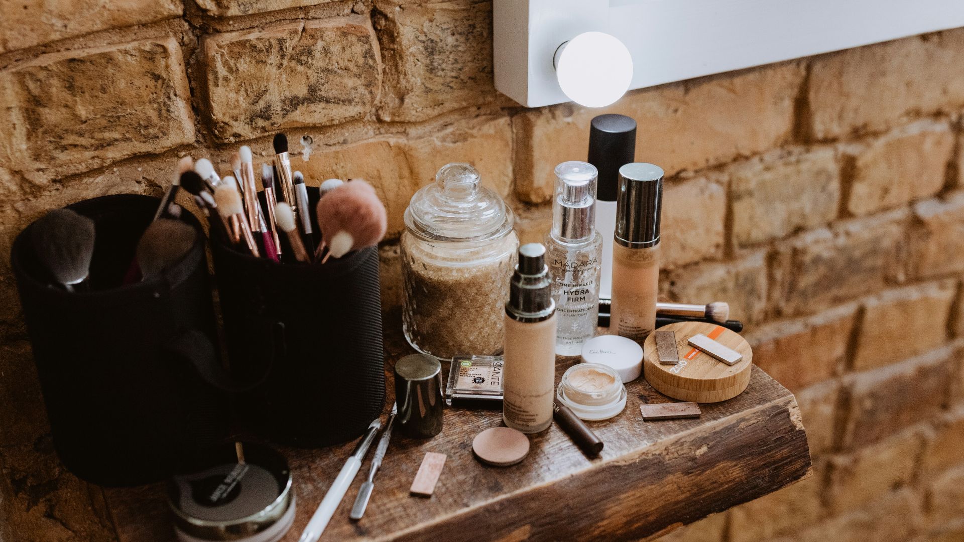 a wooden table topped with makeup and brushes