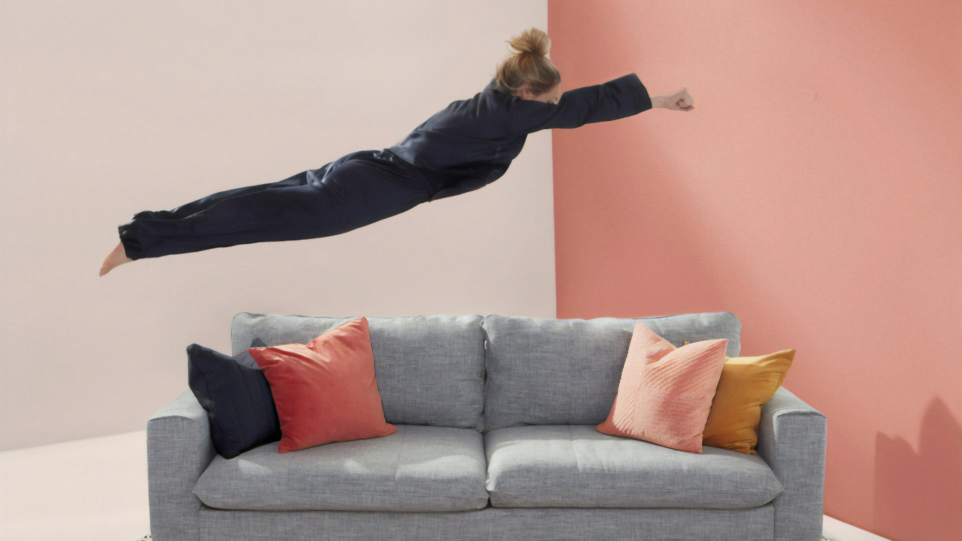 woman jumping in gray 2-seat sofa