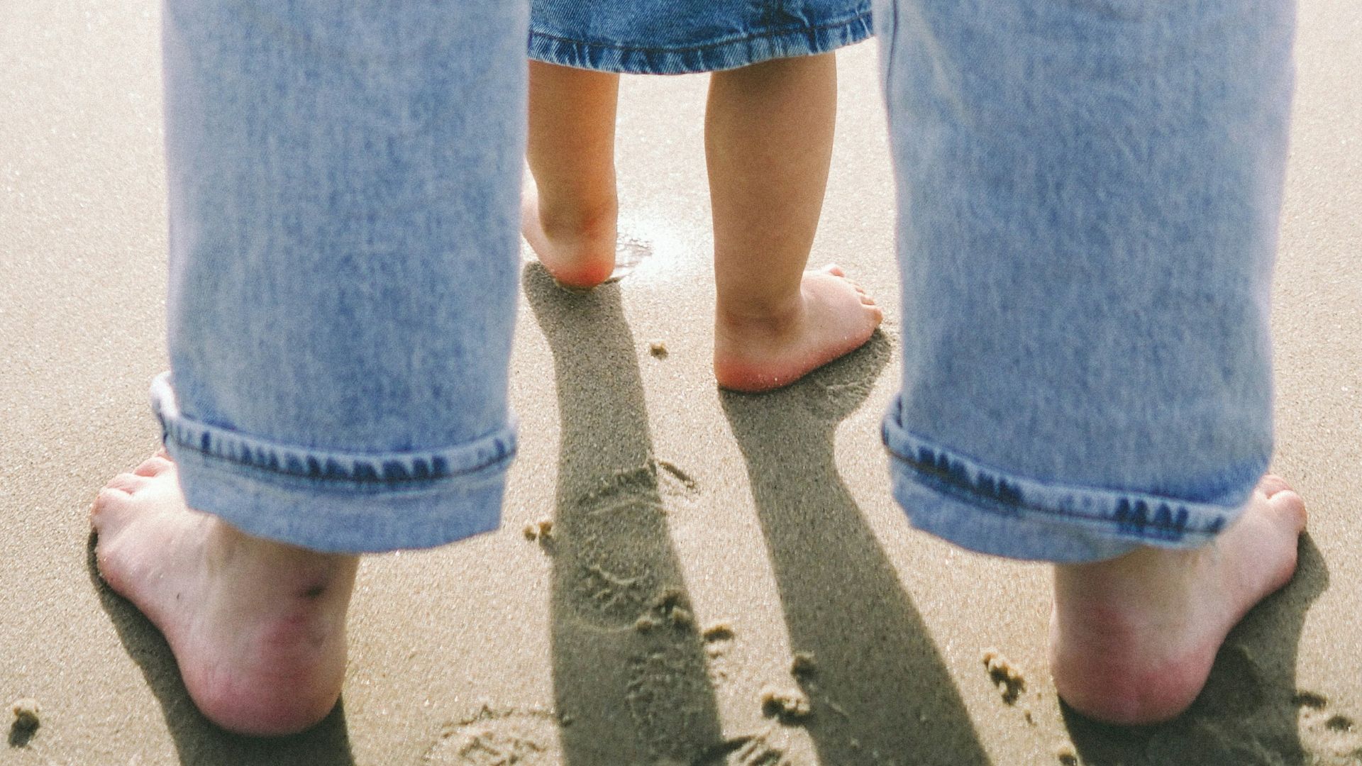 two people standing in the sand on the beach