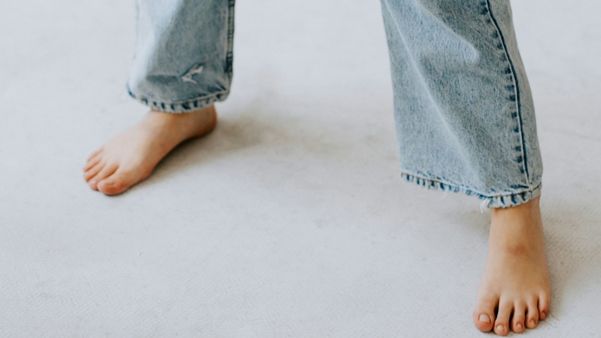 a person standing on a white floor wearing jeans and a black shirt