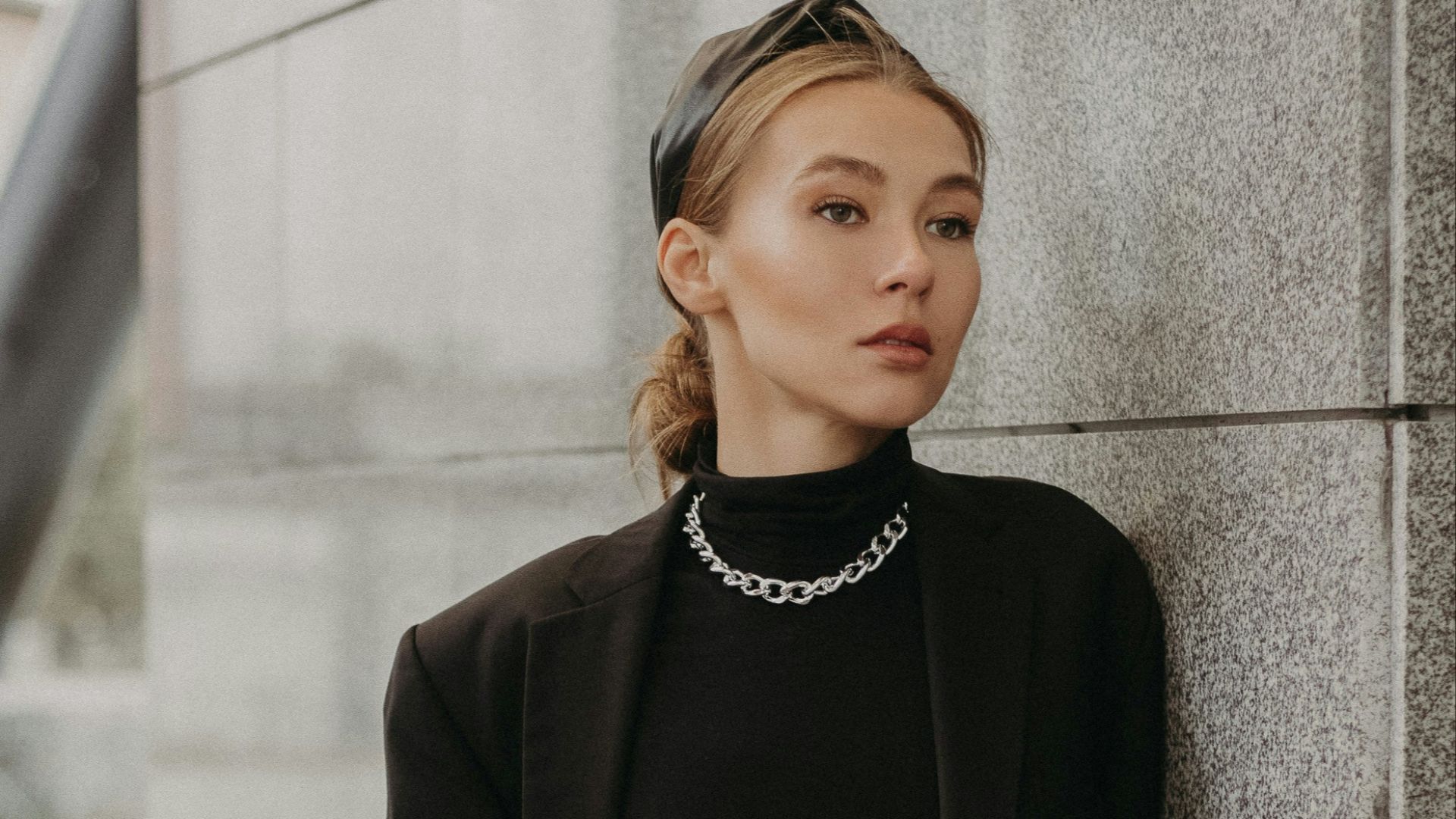 woman in black long sleeve dress leaning on gray concrete wall during daytime