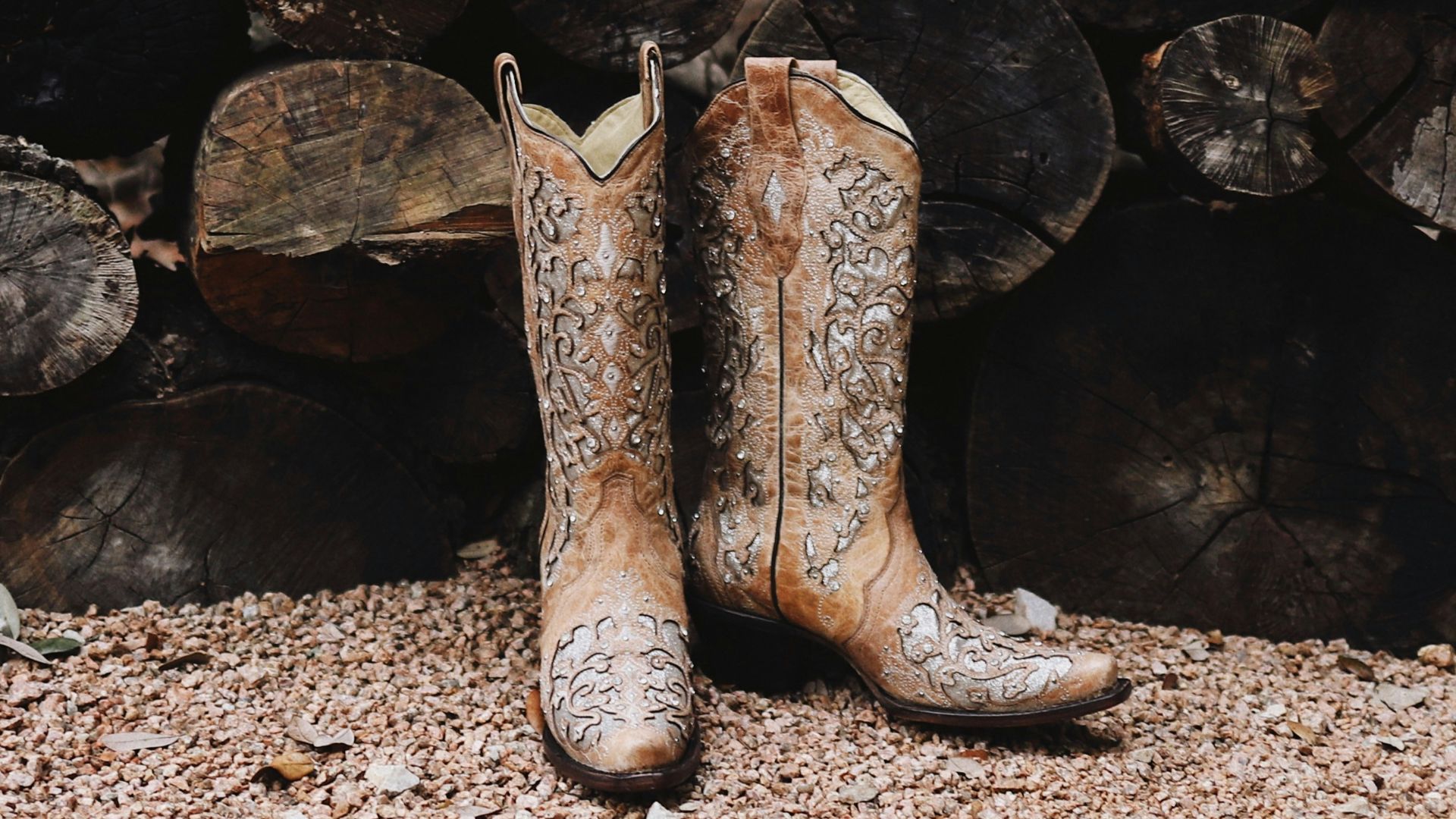 pair of brown leather cowboy boots near firewood