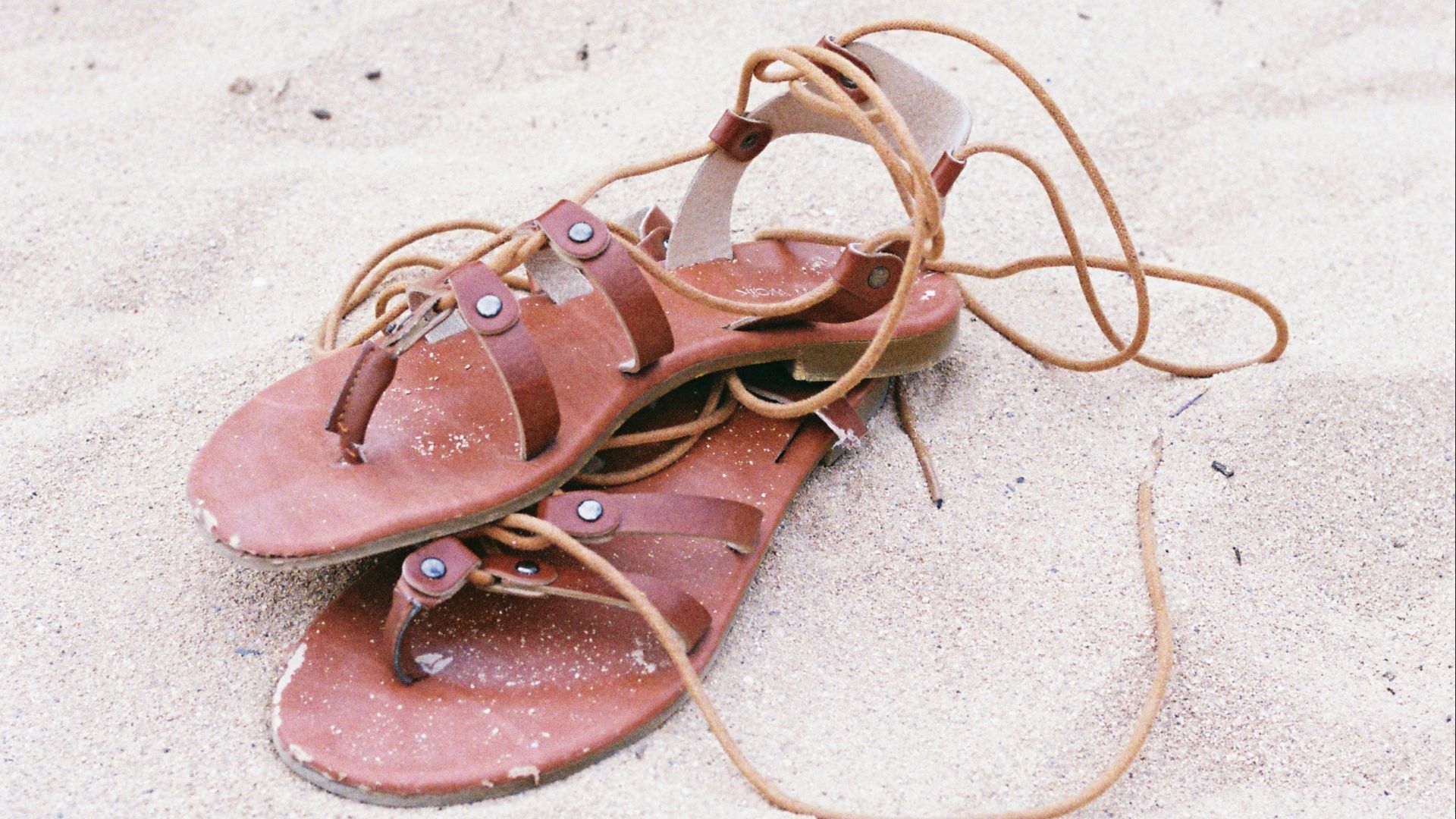 A pair of pink sandals sitting on top of a sandy beach