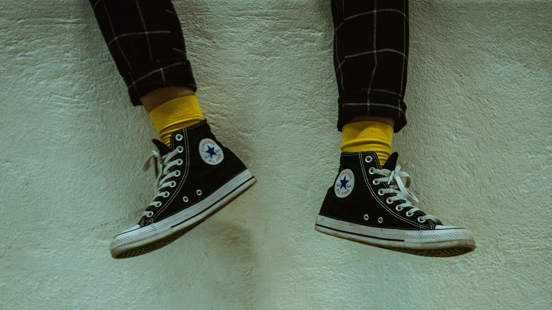person wearing white-and-black Converse high-top sneakers