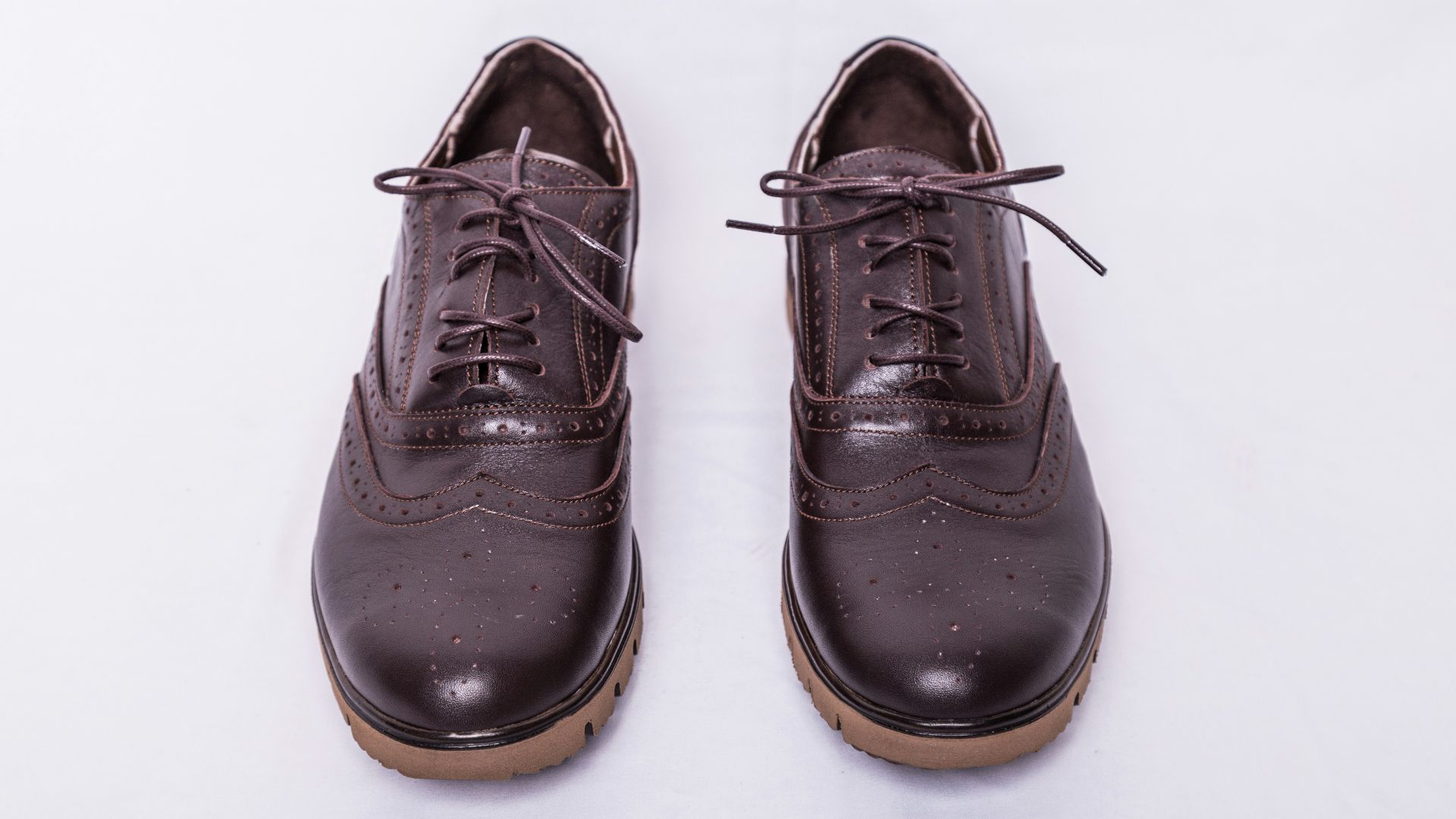 a pair of brown shoes on a white surface