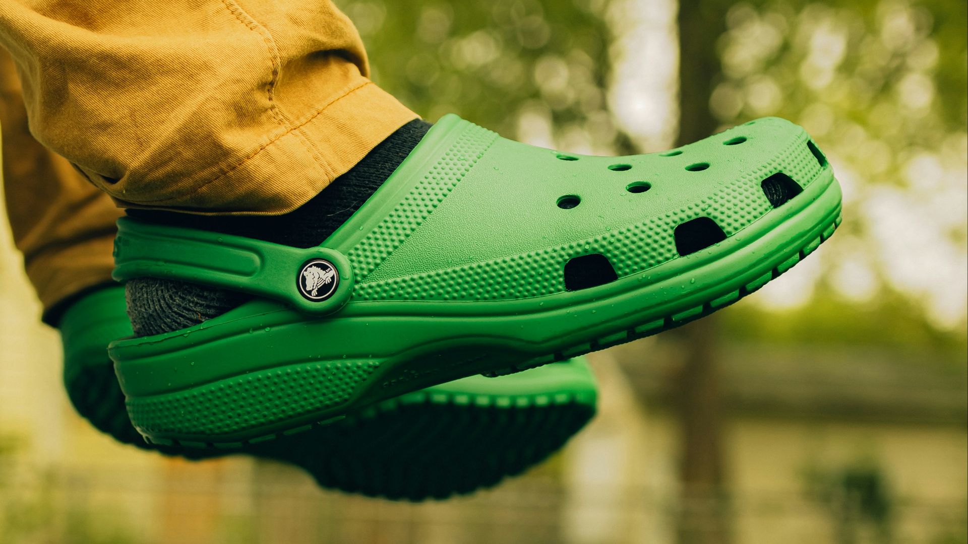a person wearing a green clogger shoe in a park