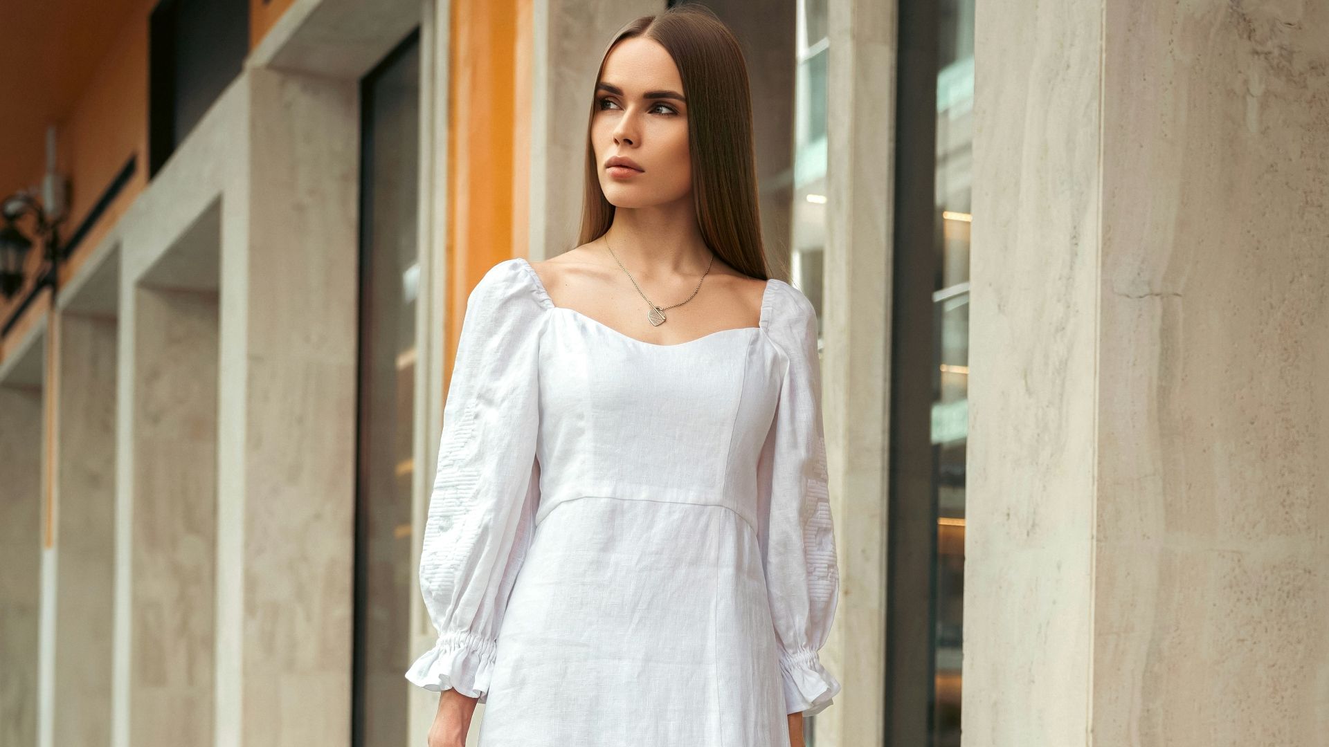 Woman walks confidently in a stylish white dress.