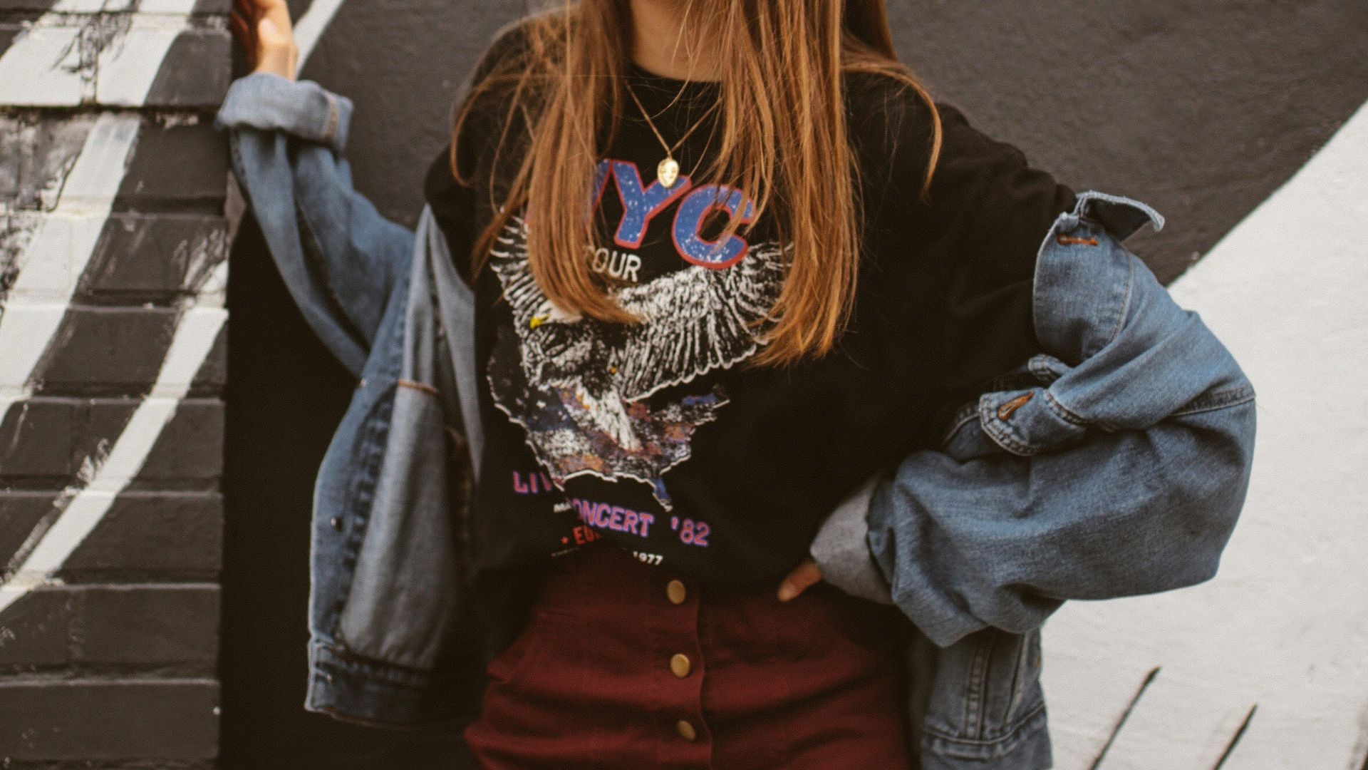woman wearing blue denim jacket standing beside wall