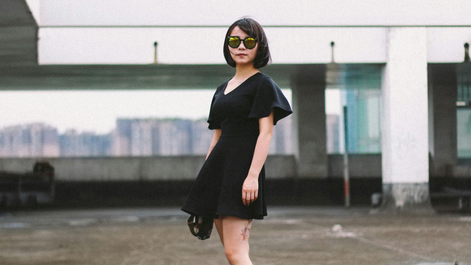 woman in black minidress and black sunglasses standing on street