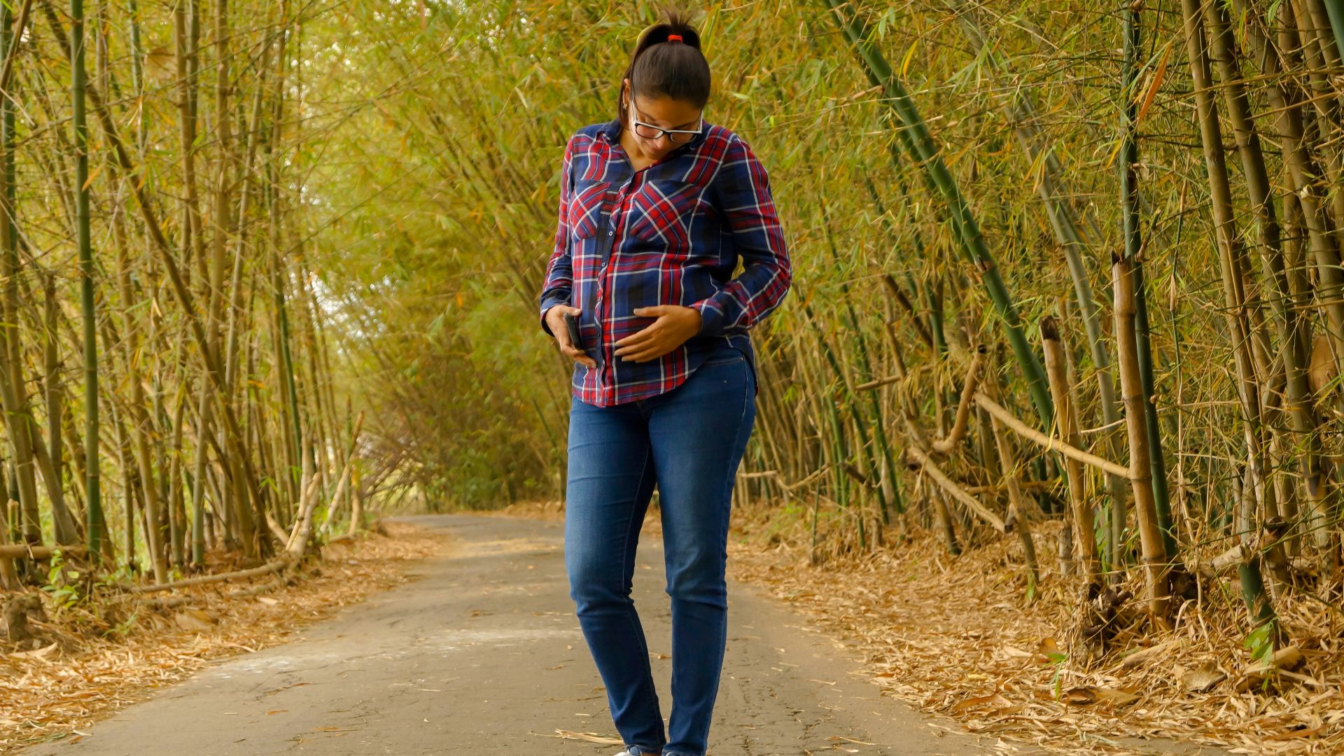 man in red and blue plaid dress shirt and blue denim jeans standing on road during
