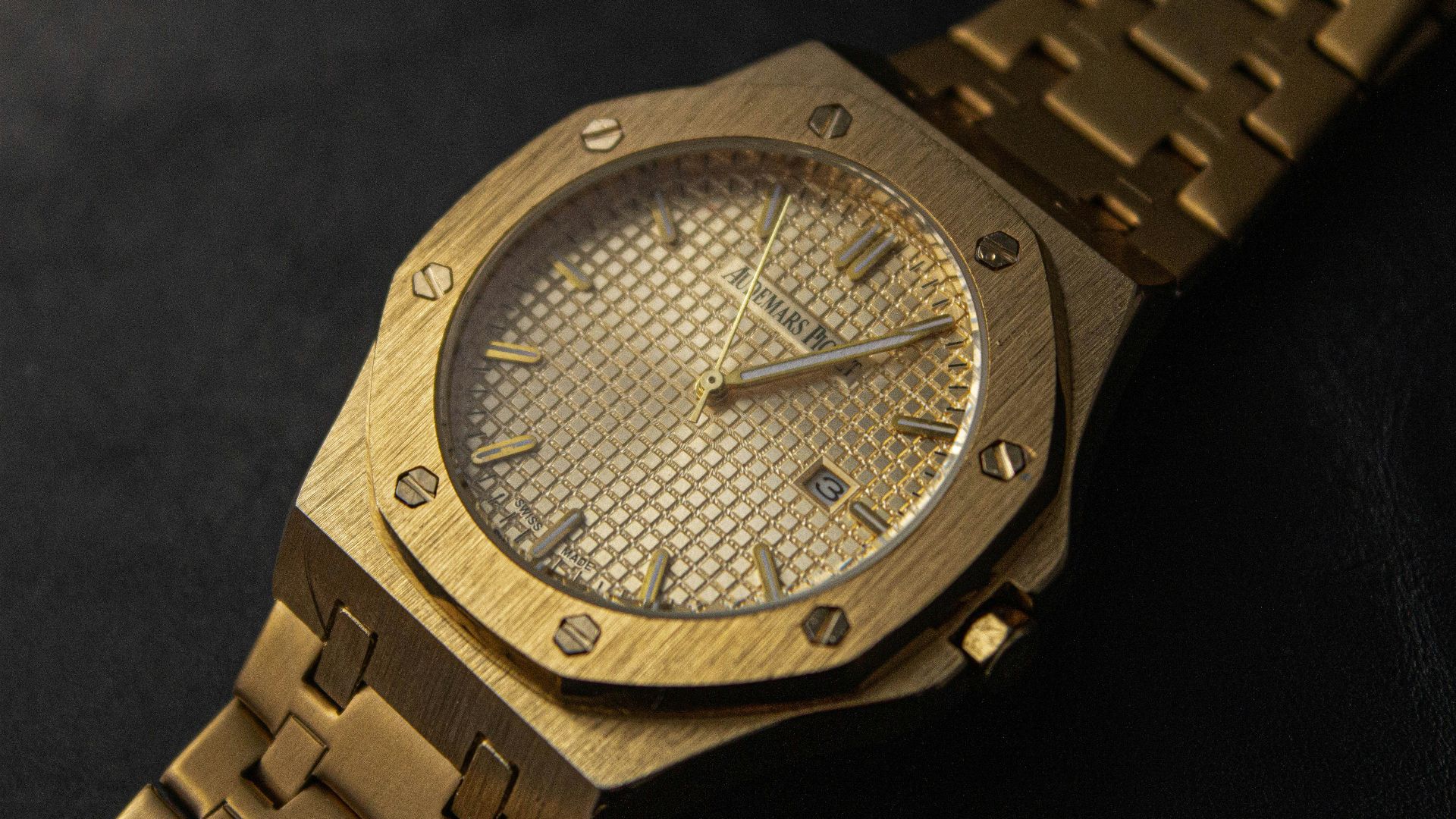 a gold watch sitting on a black surface