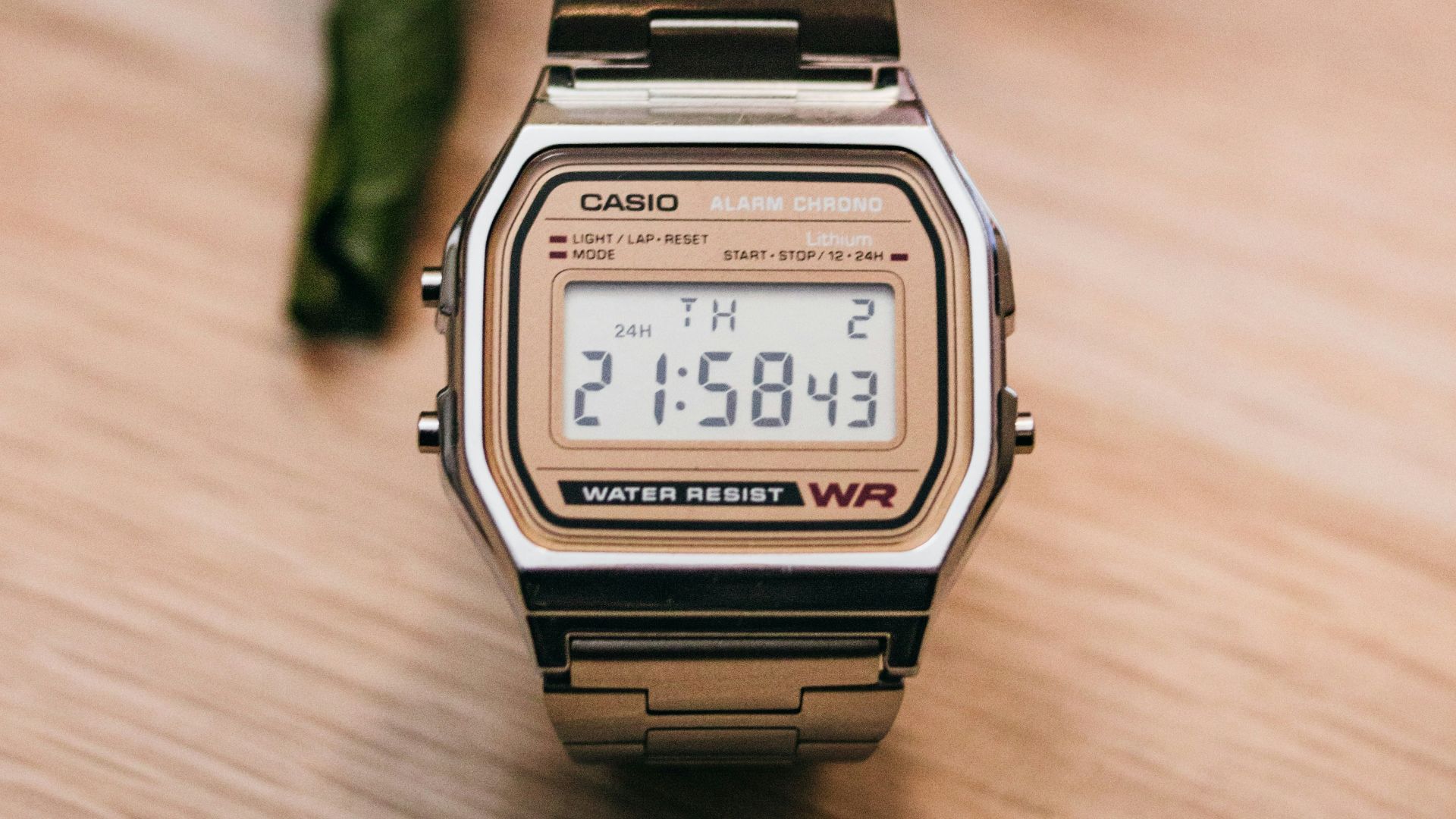 brown and silver Casio digital watch on wooden surface