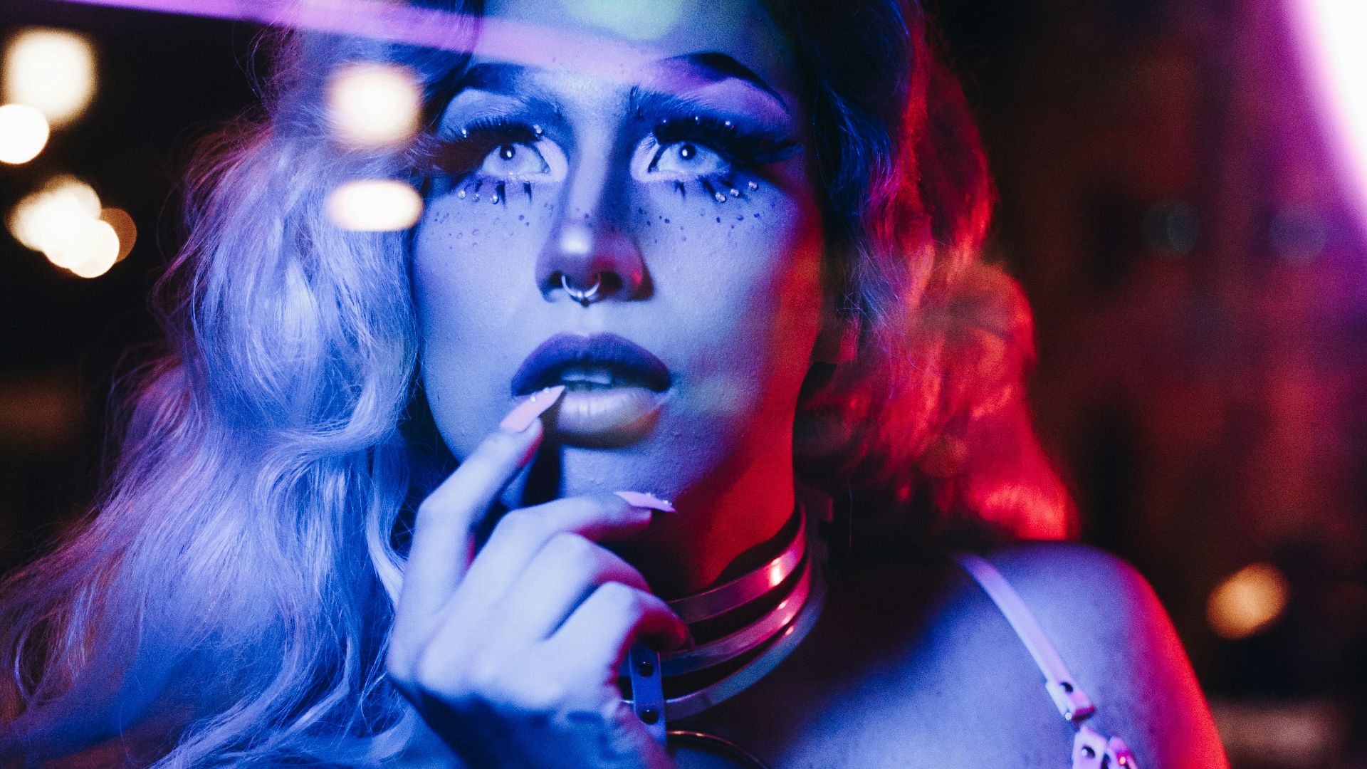 a woman in a bra top smoking a cigarette in front of a neon sign