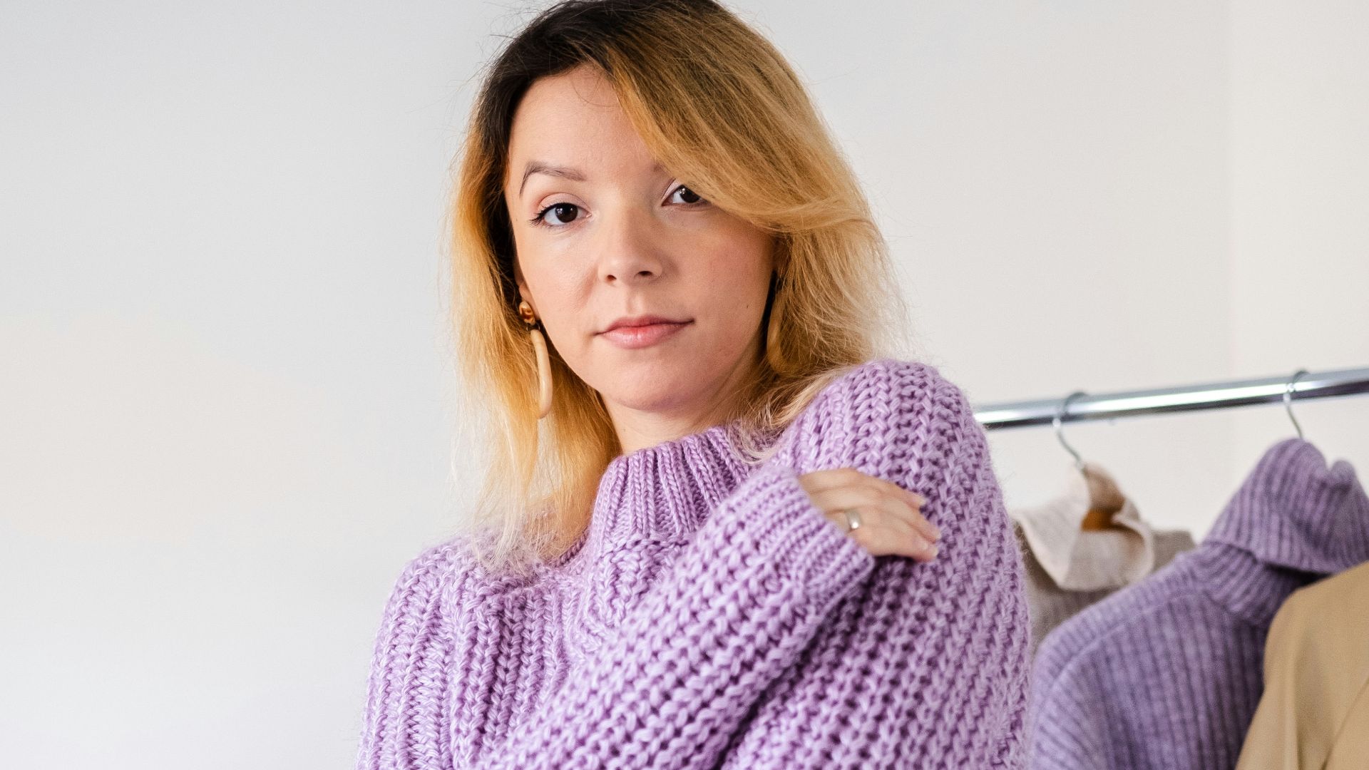 a woman standing in front of a rack of clothes