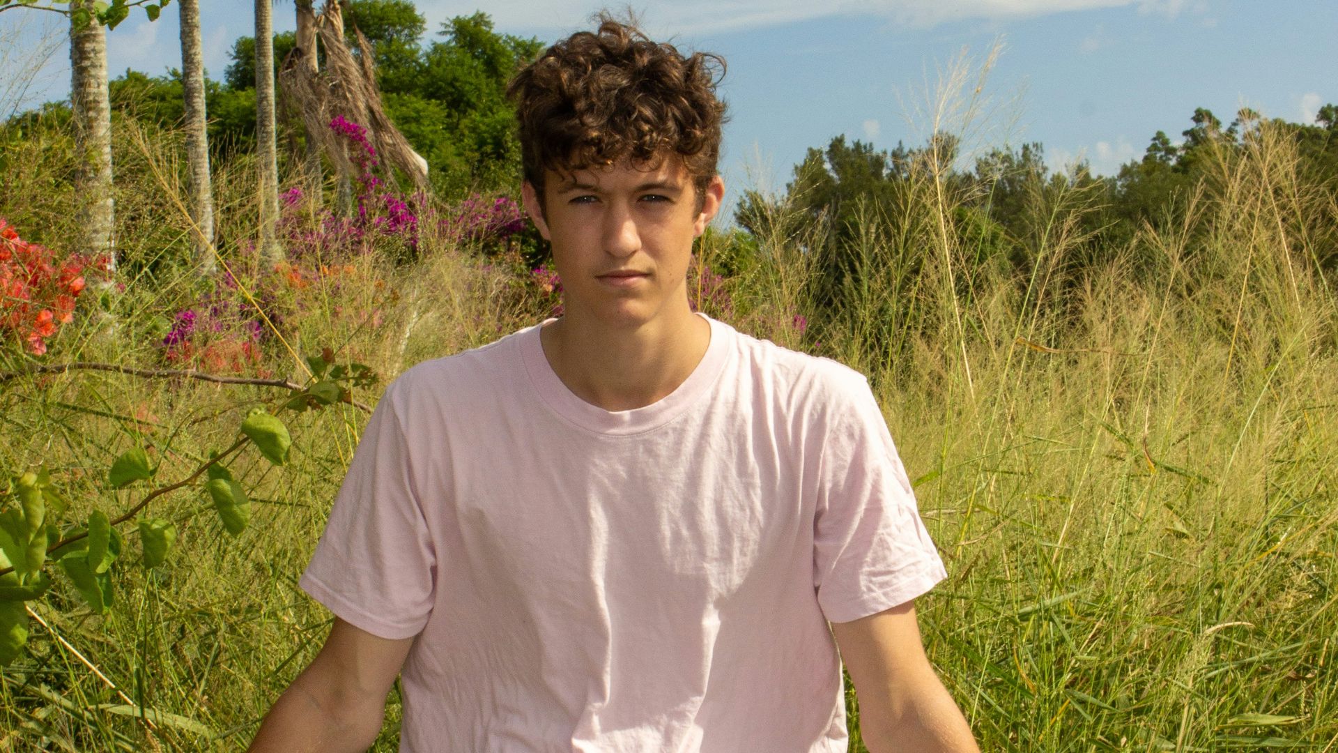 man in white crew neck t-shirt sitting on green grass during daytime