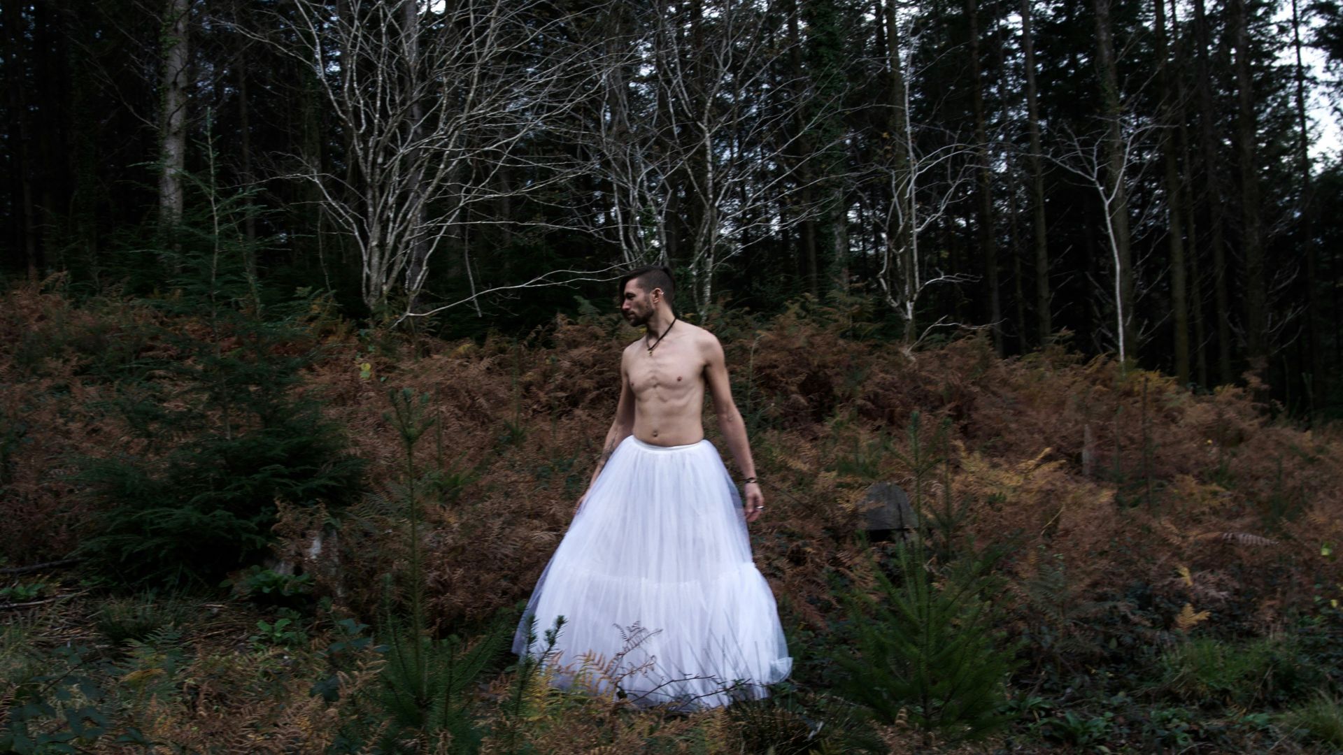 a man in a white dress standing in a forest