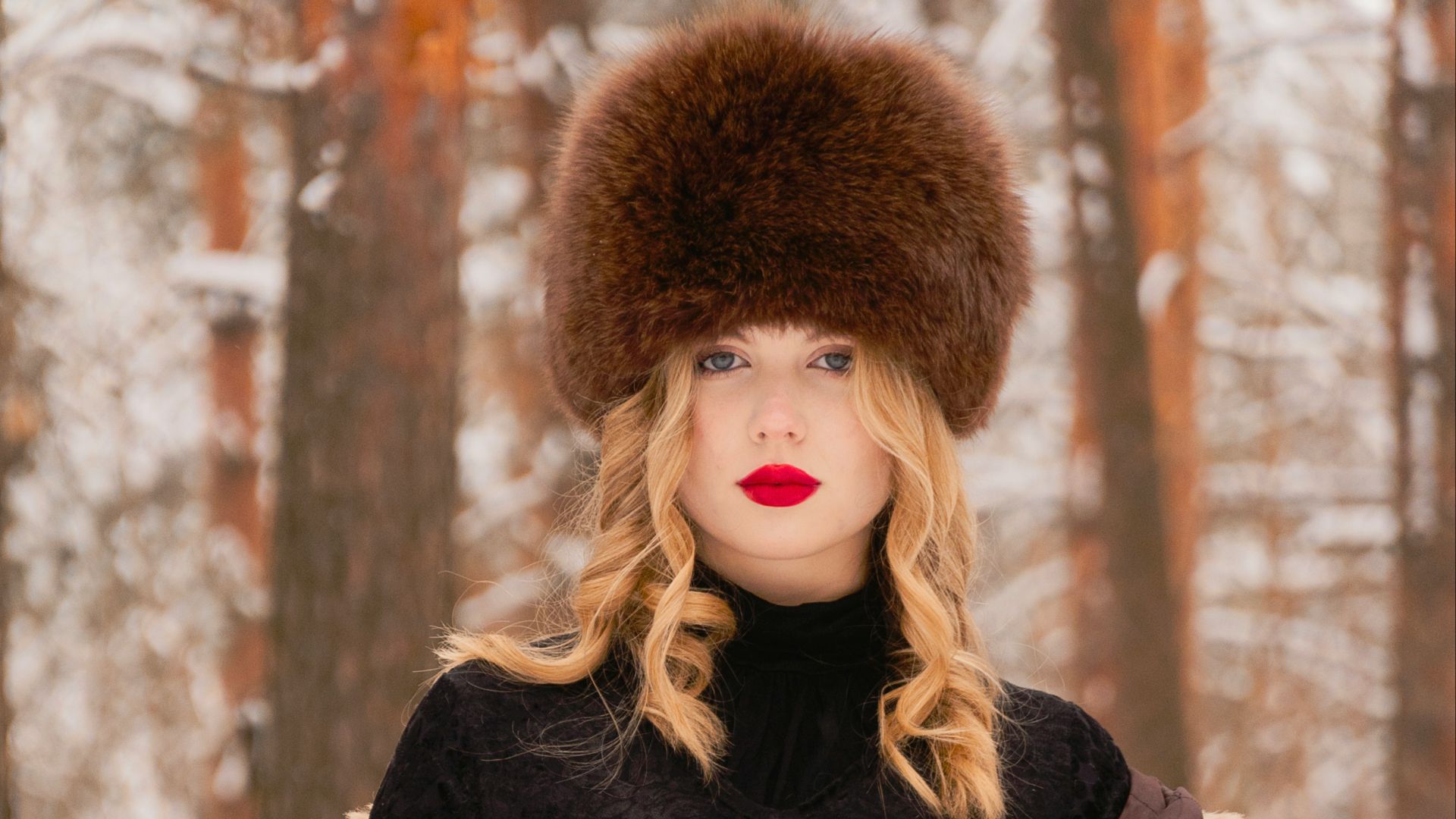 a woman in a fur coat and hat standing in the snow