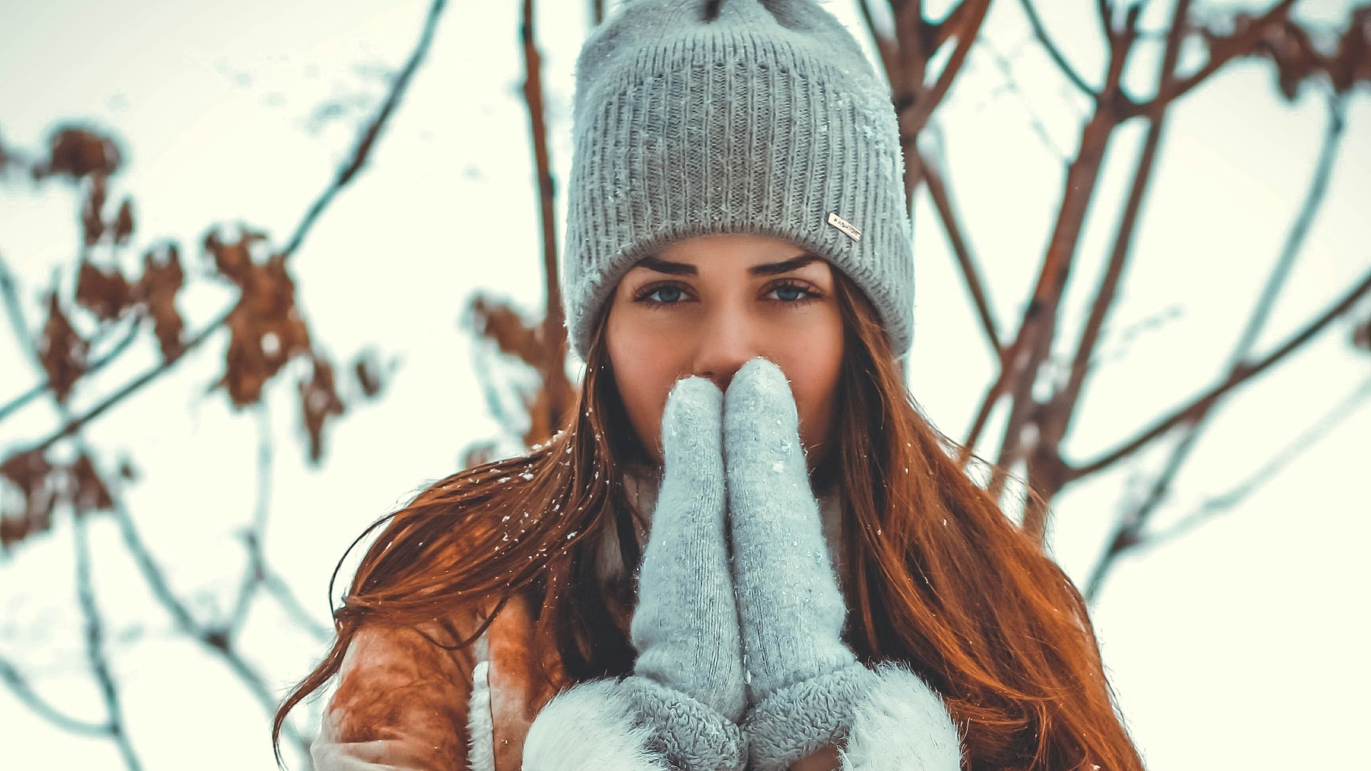 woman wearing brown jacket and gray knit cap standing near tree