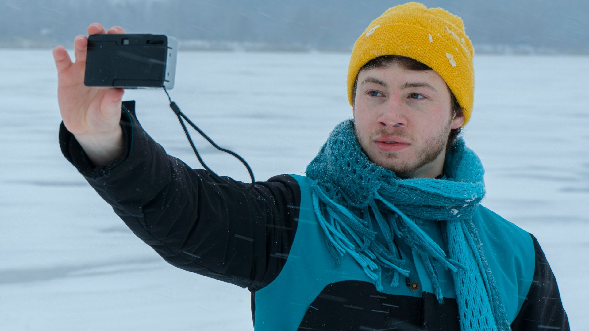 a man standing in the snow holding a camera