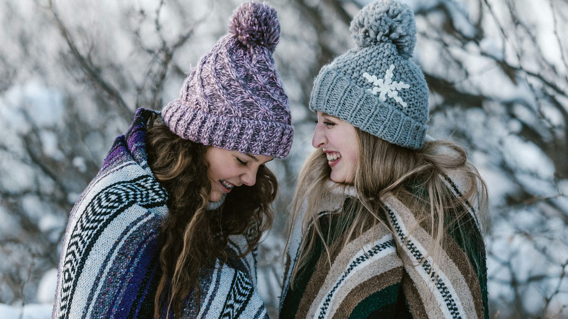 two women in multicolored striped blanket standing near tree