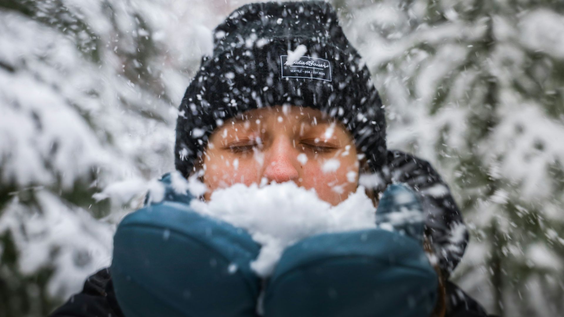 a woman blowing snow in front of her face