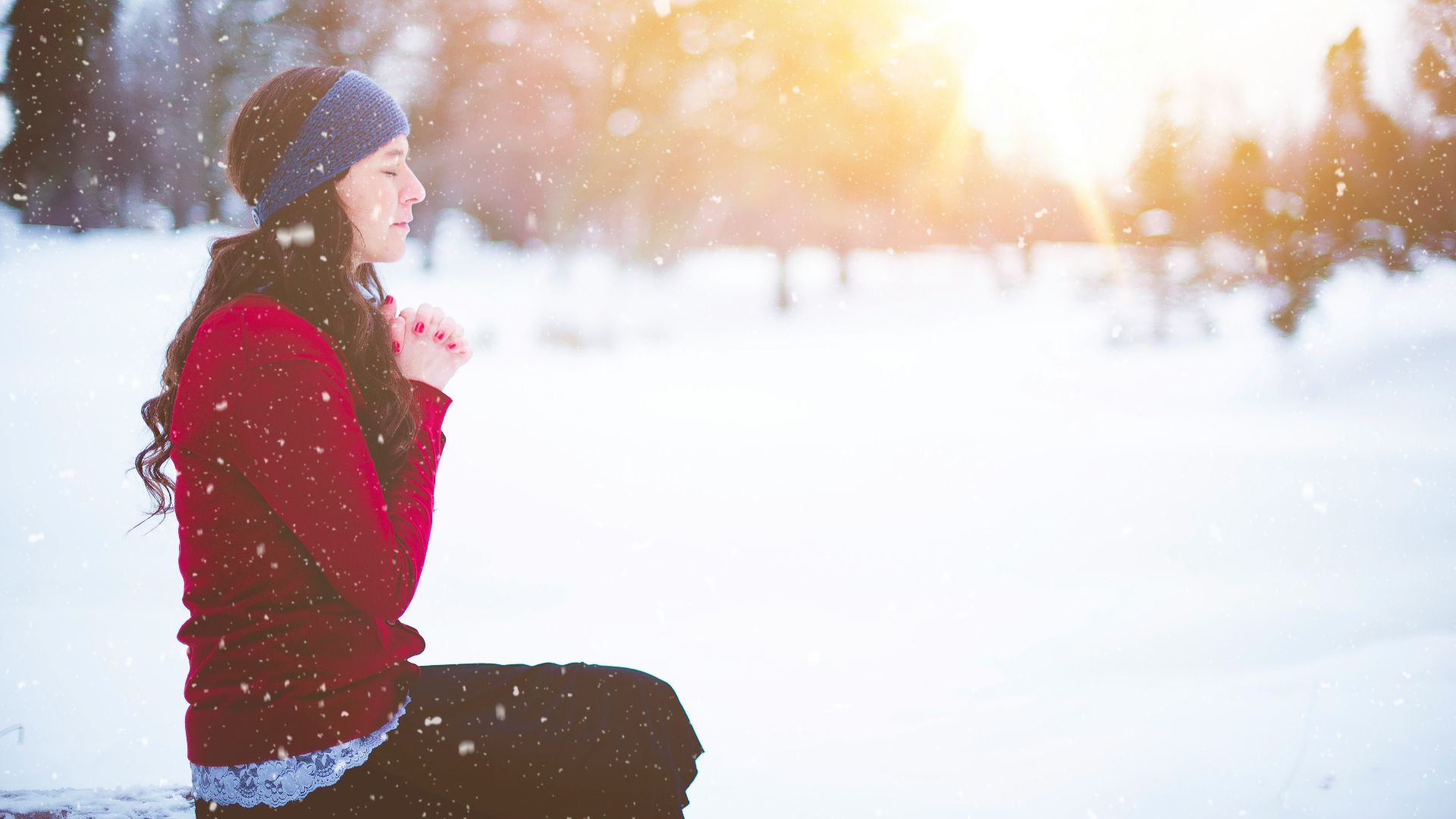 woman sitting with closed eyes surrounded by snow