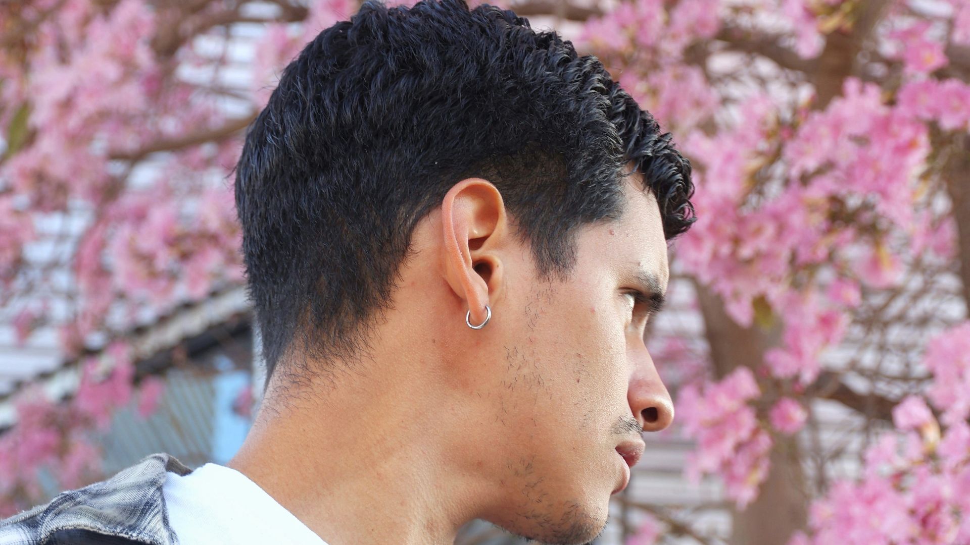 A man poses near pink blossoms.