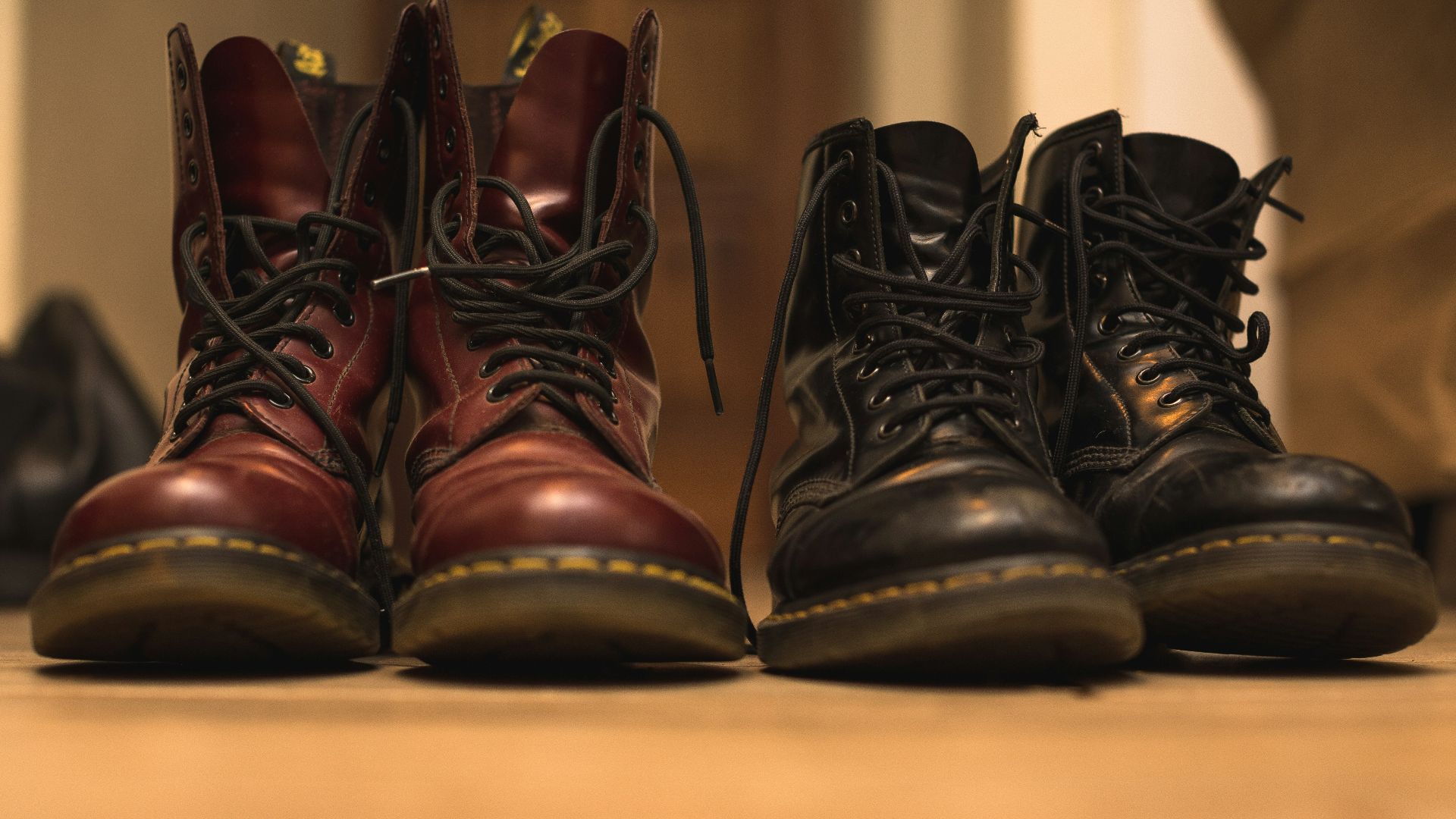 two pair of black and brown leather work boots on brown surface