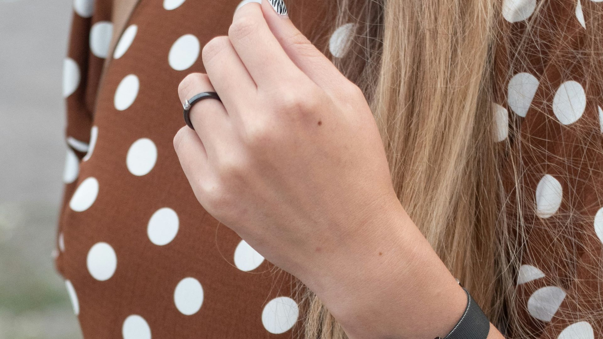 a woman wearing a brown and white polka dot dress
