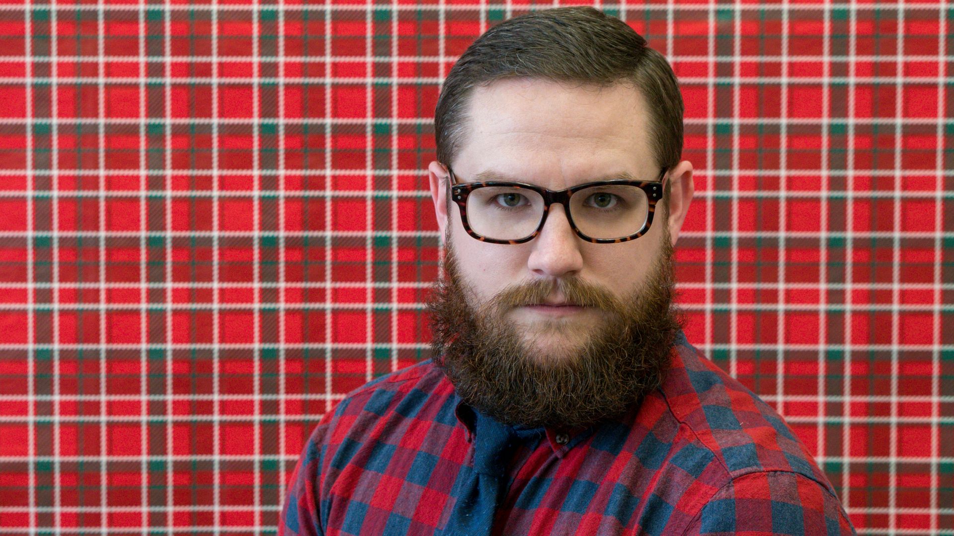 man wearing eyeglasses near red wall
