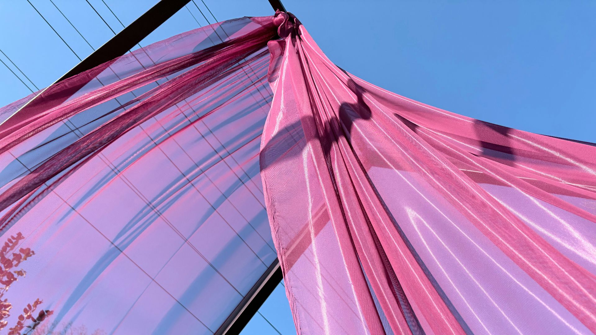 Pink fabric draped against a clear blue sky.