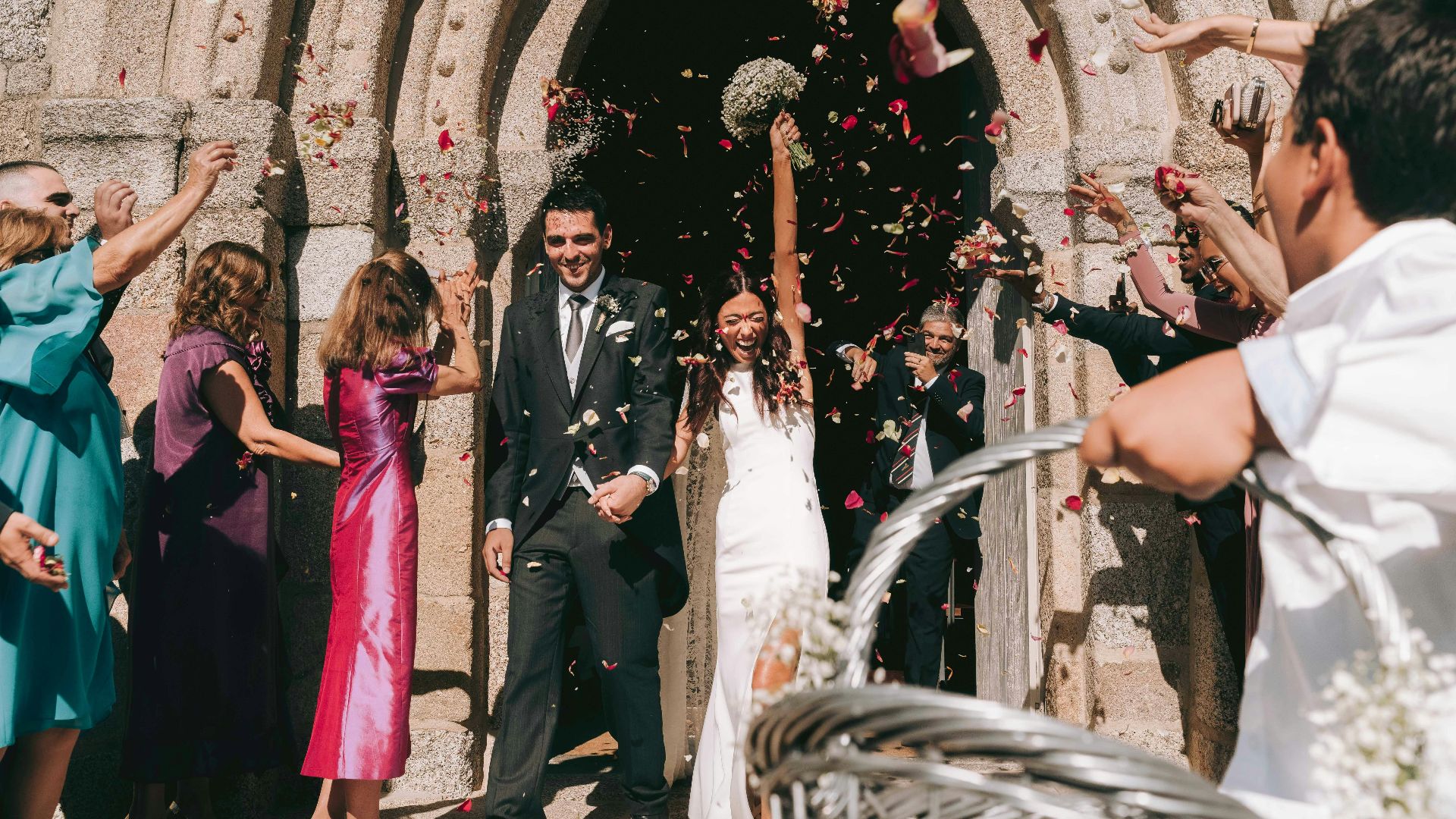 Newlyweds showered with petals leaving church.