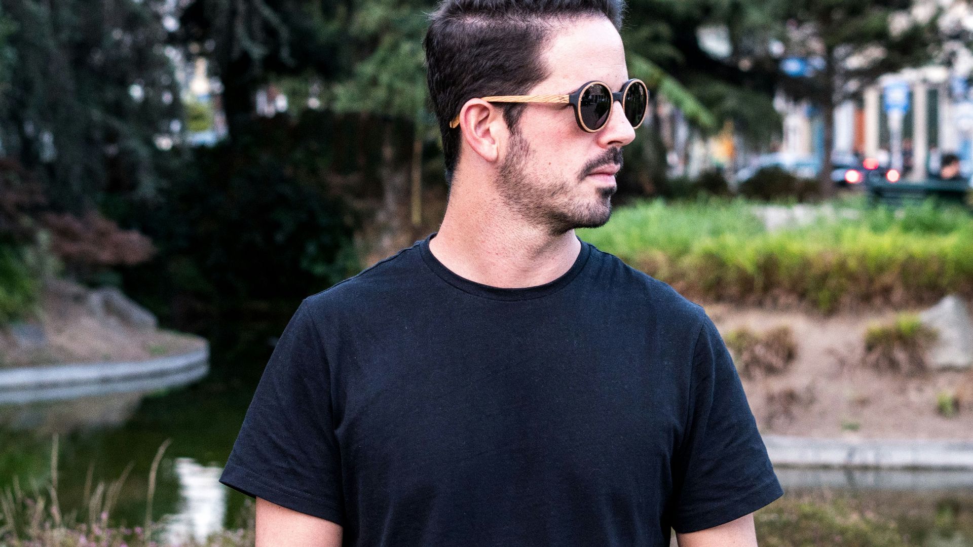 A man in a black t - shirt is holding a skateboard