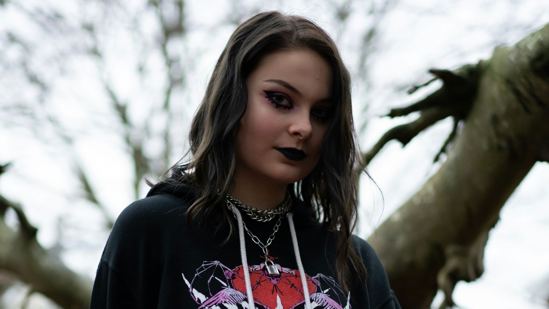woman in black and white long sleeve shirt sitting beside brown tree during daytime