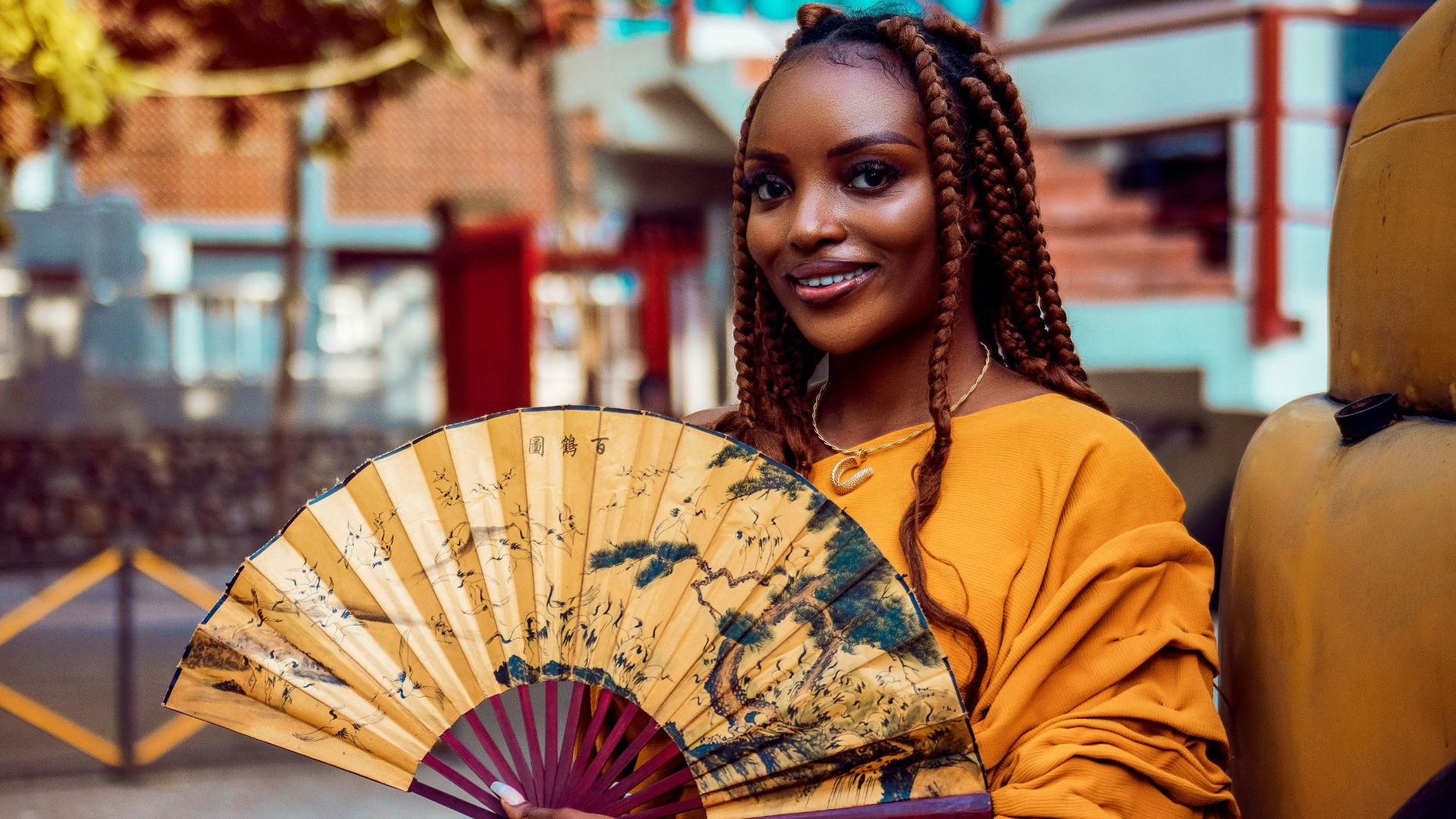 a woman in a yellow dress holding a fan