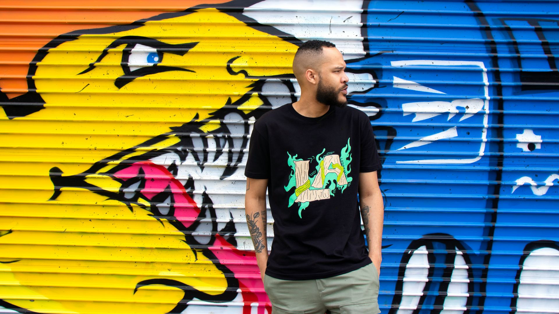 man in black crew neck t-shirt standing beside yellow and blue surfboard