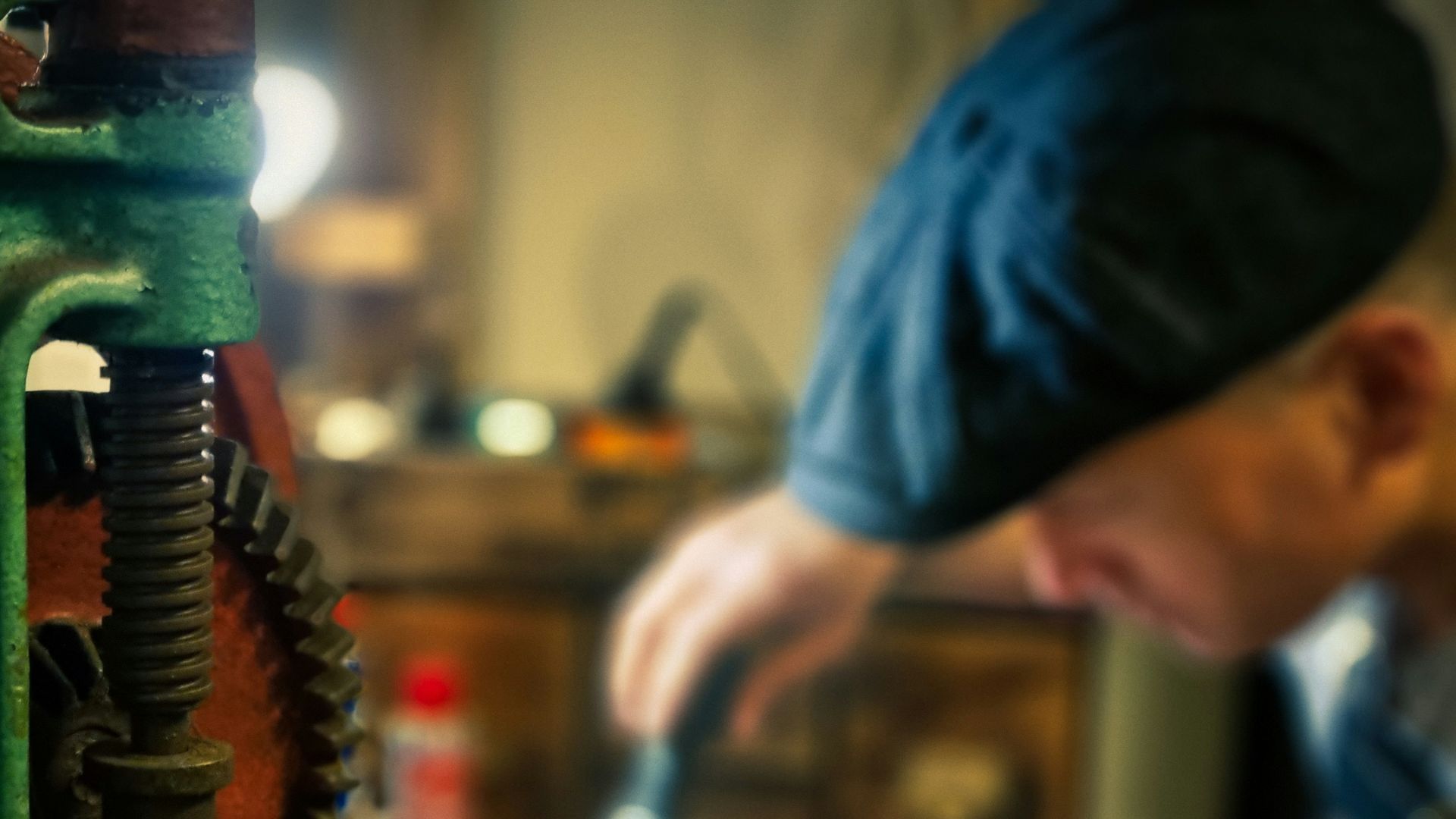 person in blue shirt holding green and silver power tool