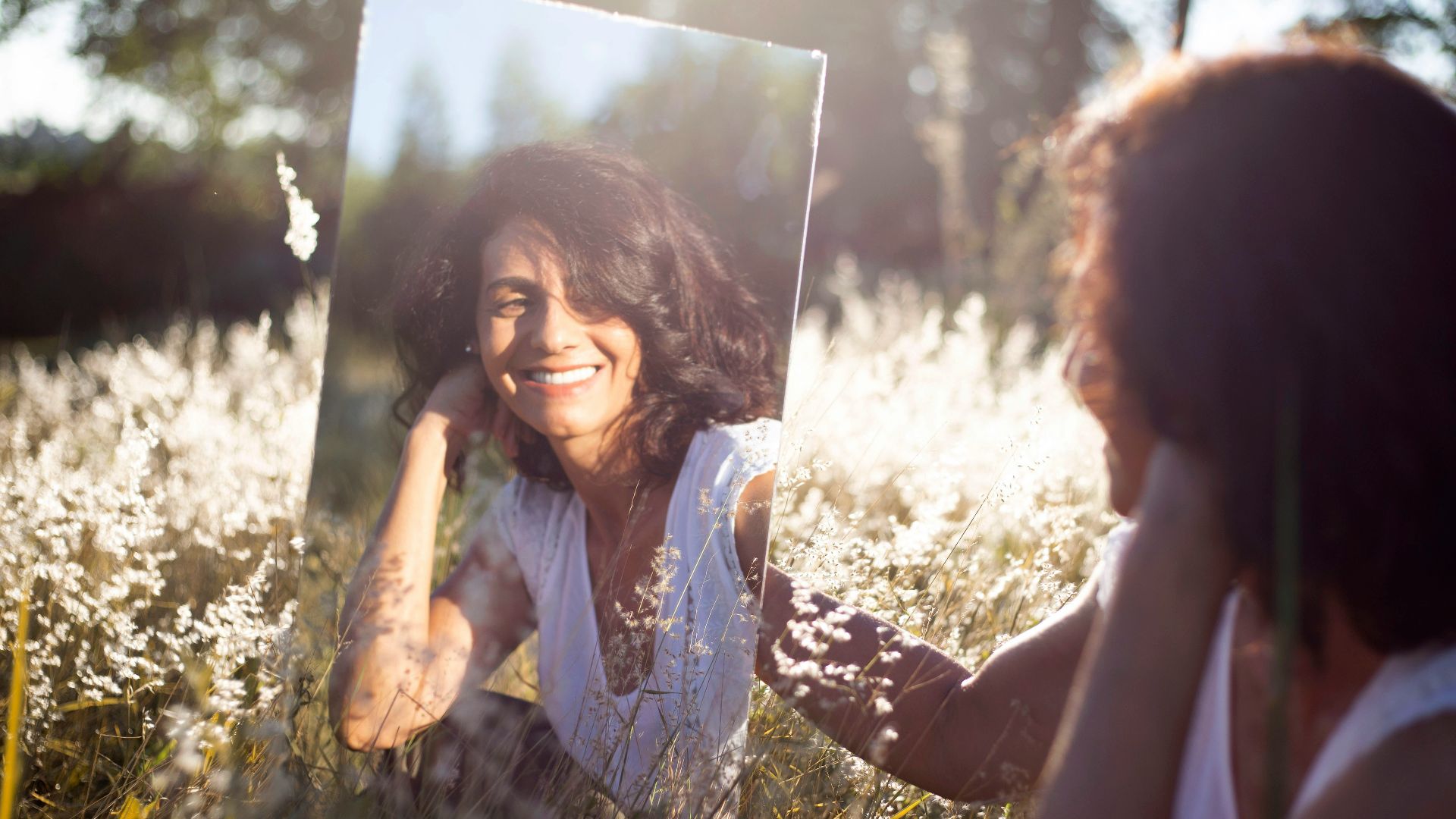 woman in blue and white floral shirt holding her face