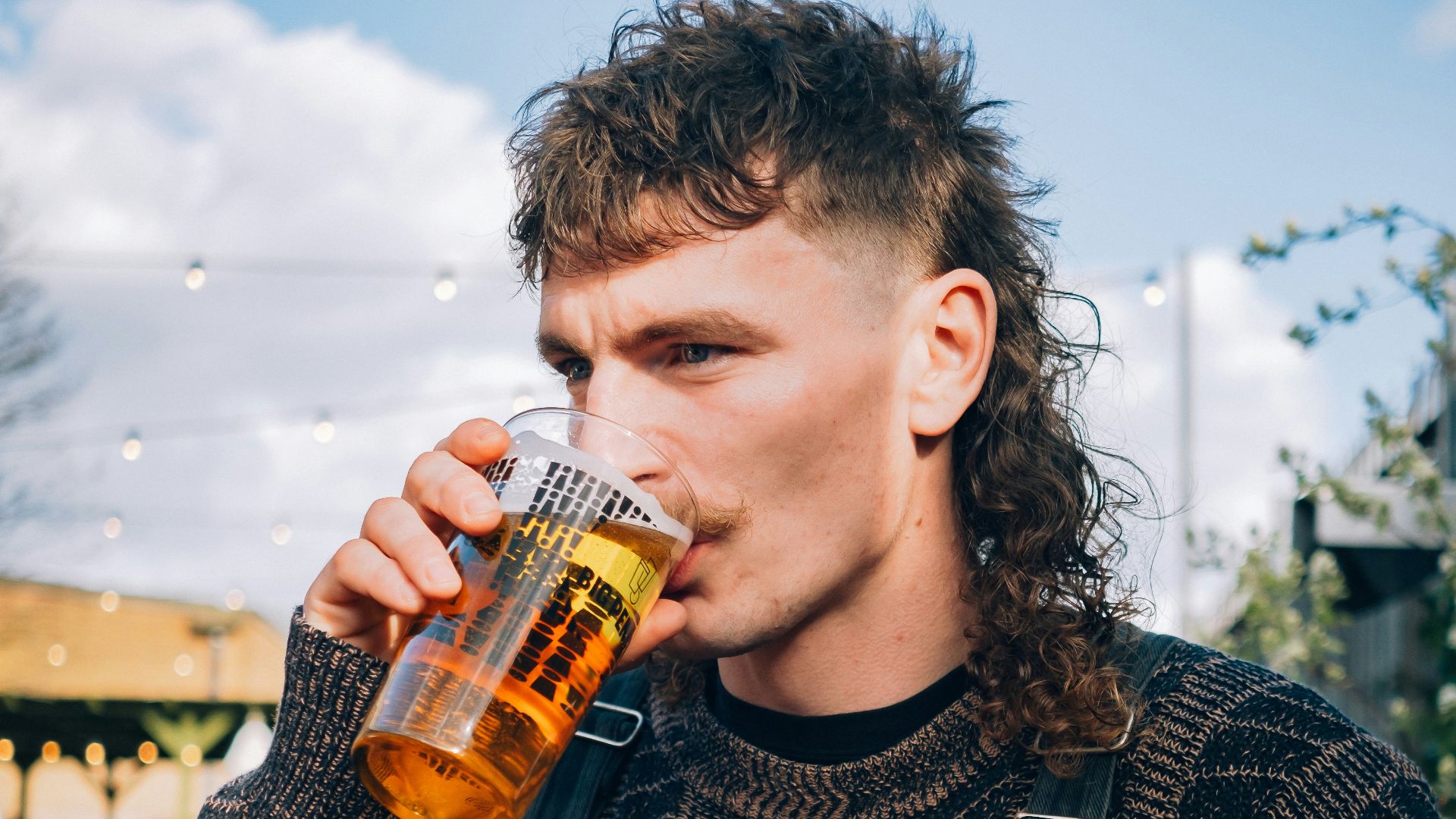 a man with long hair drinking a beer
