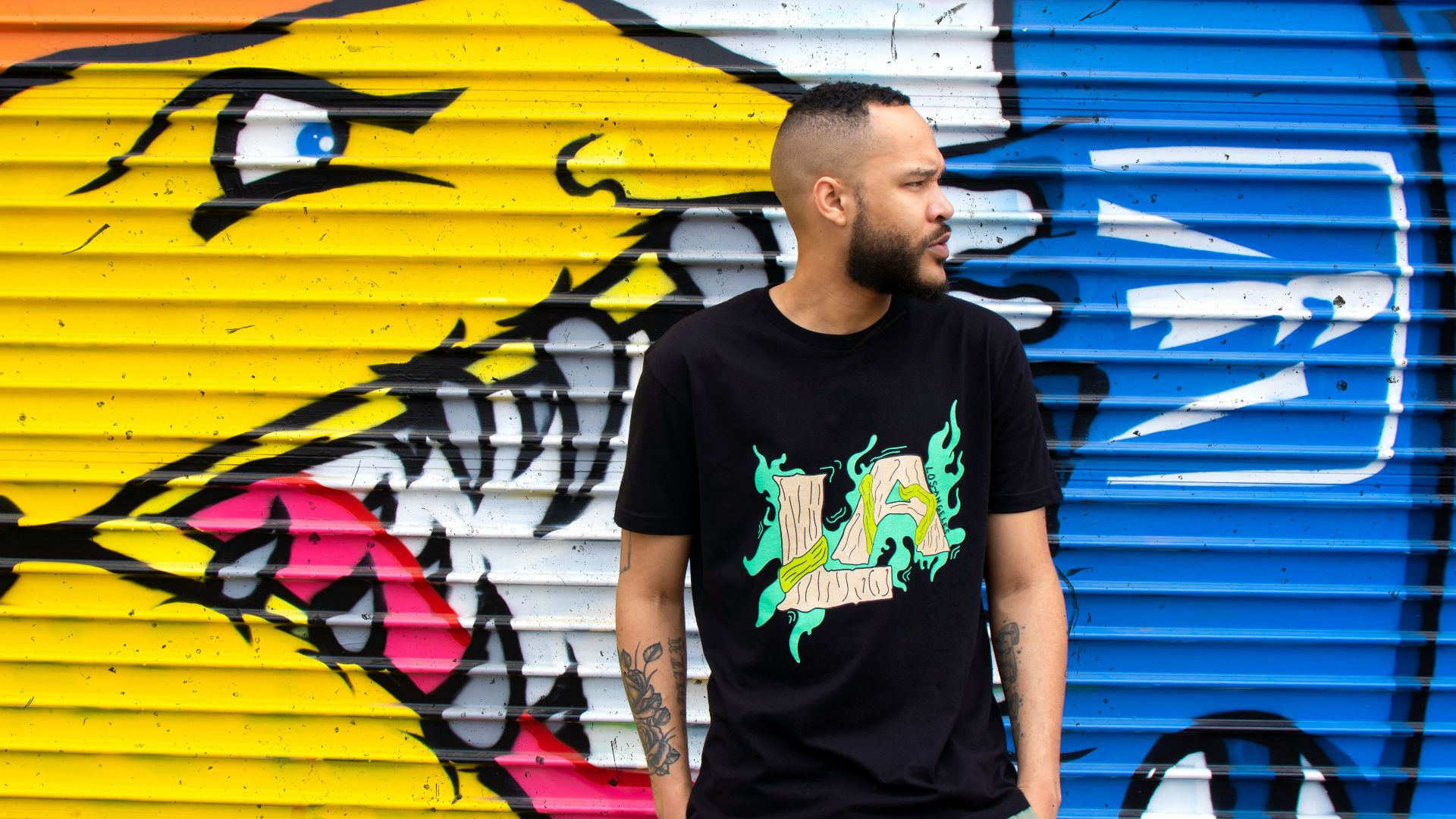 man in black crew neck t-shirt standing beside yellow and blue surfboard