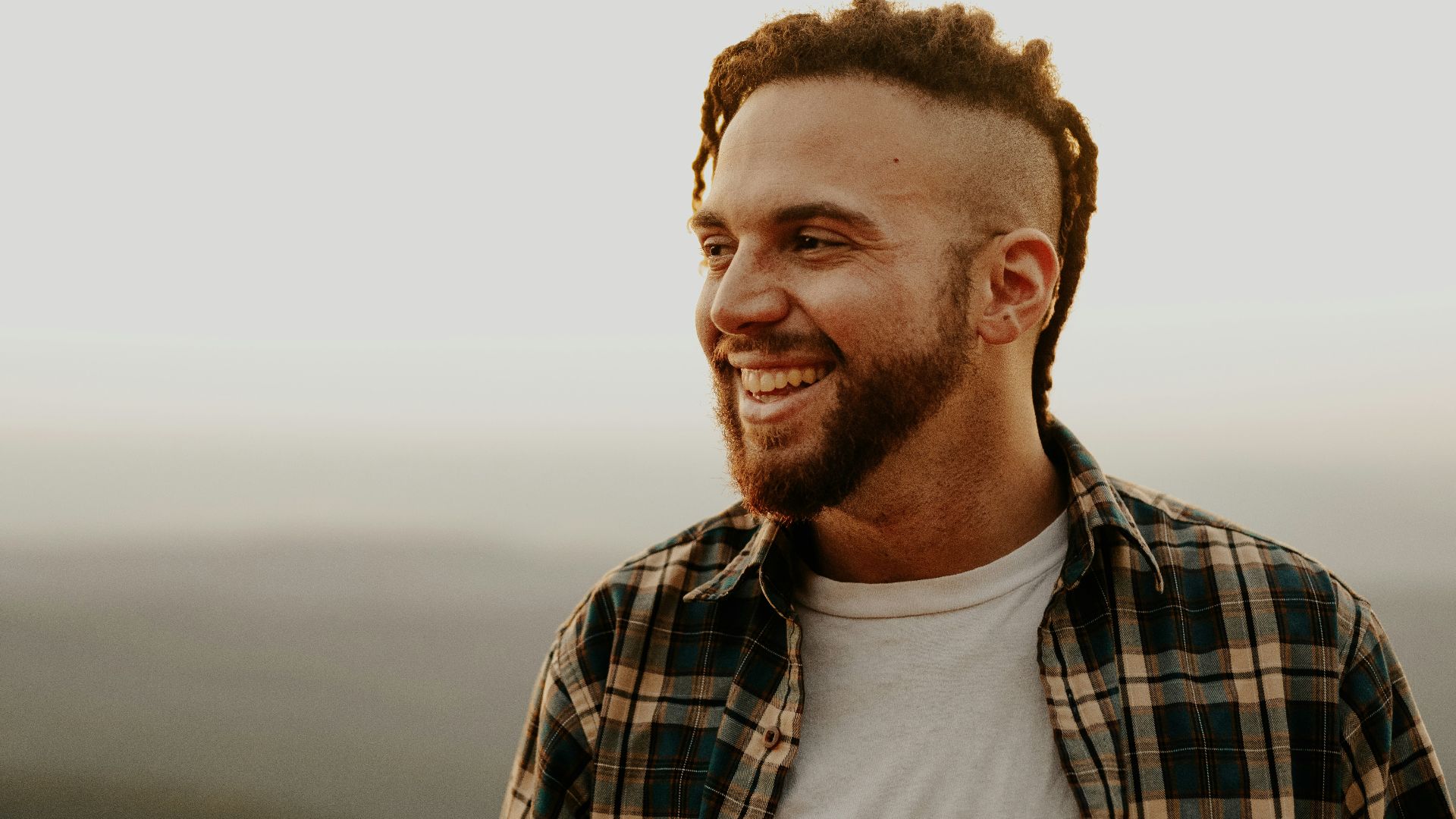 a man with dreadlocks smiles at the camera