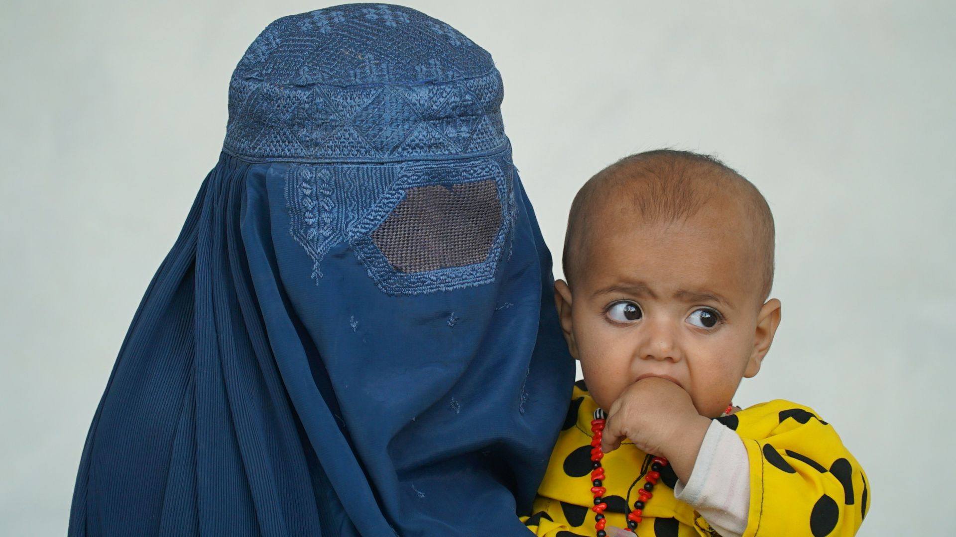 a baby wearing a yellow shirt and a blue head covering