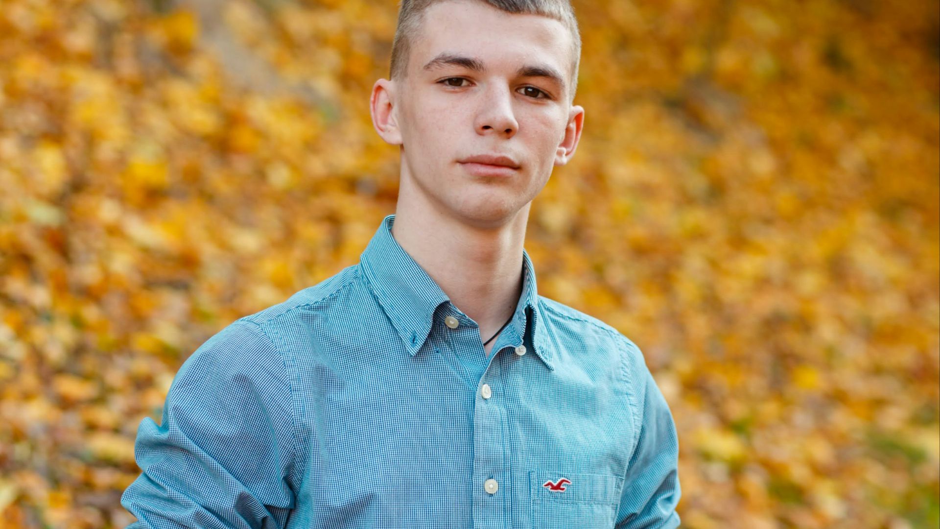 man in blue dress shirt standing near brown leaves during daytime