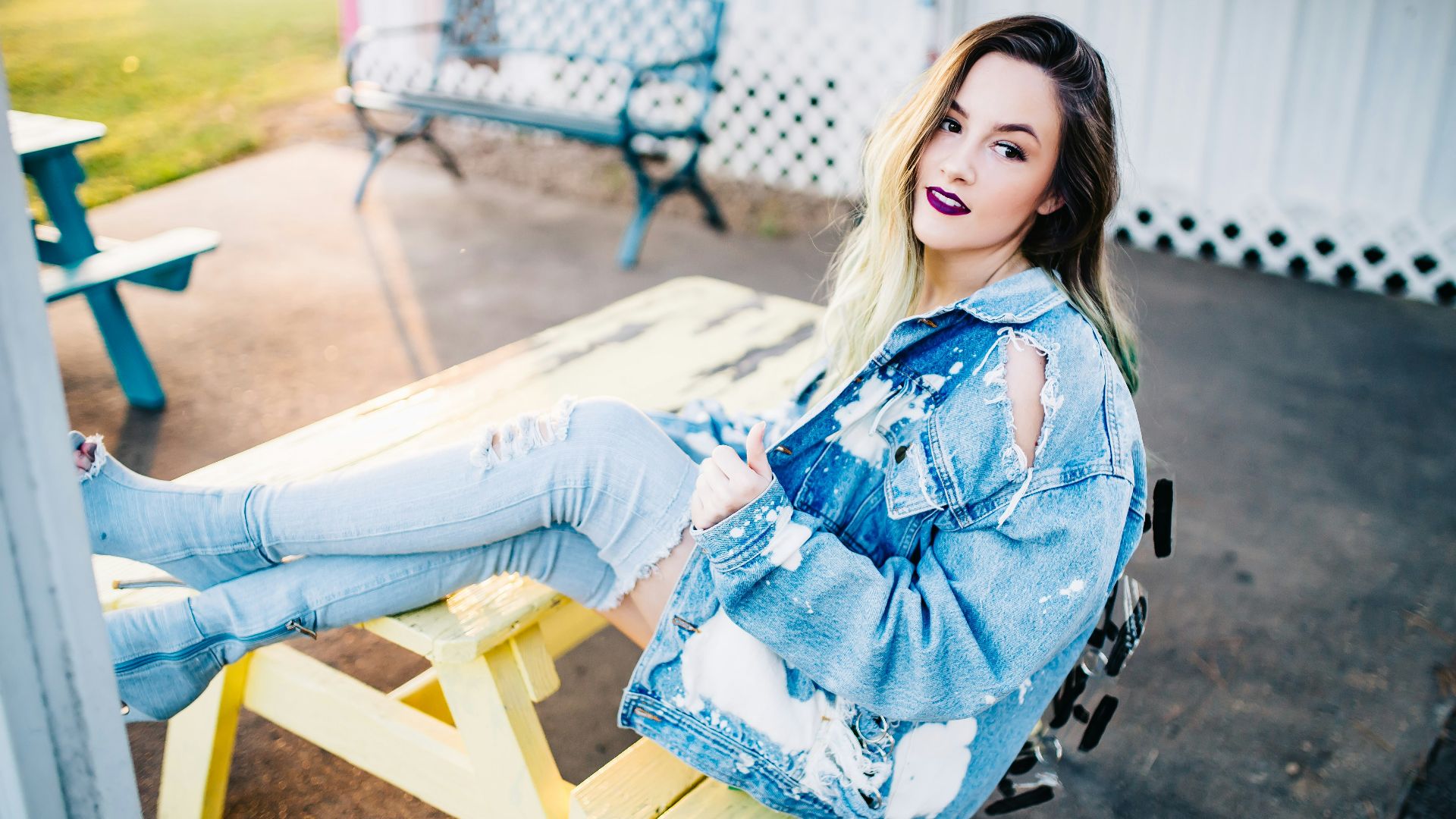 smiling woman sitting on yellow picnic table during daytime