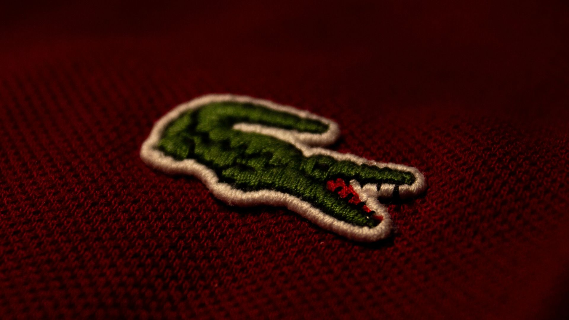 a close up of a red polo shirt with a green alligator embroidered on it
