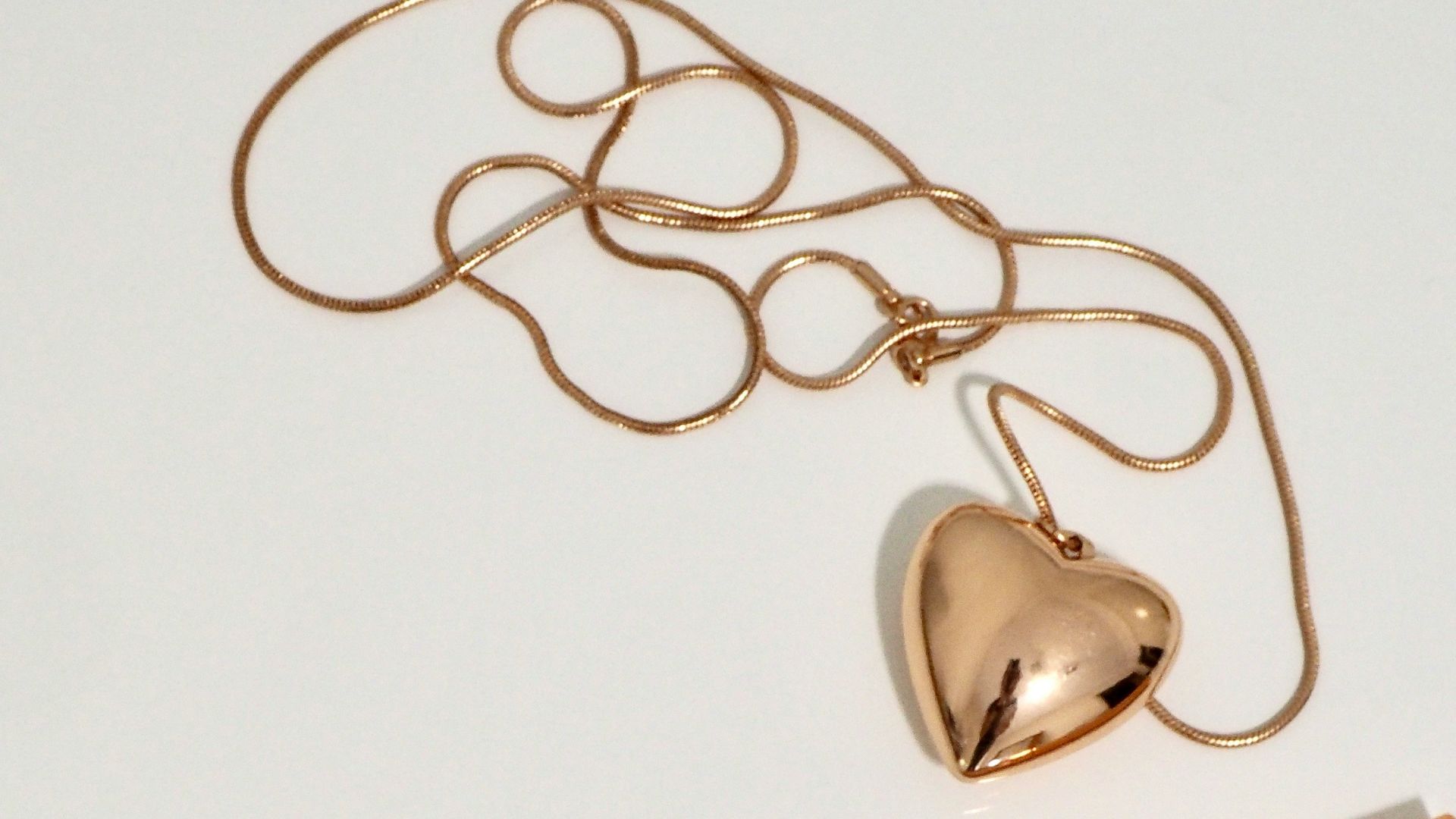 gold heart pendant necklace and two gold handled makeup brushes