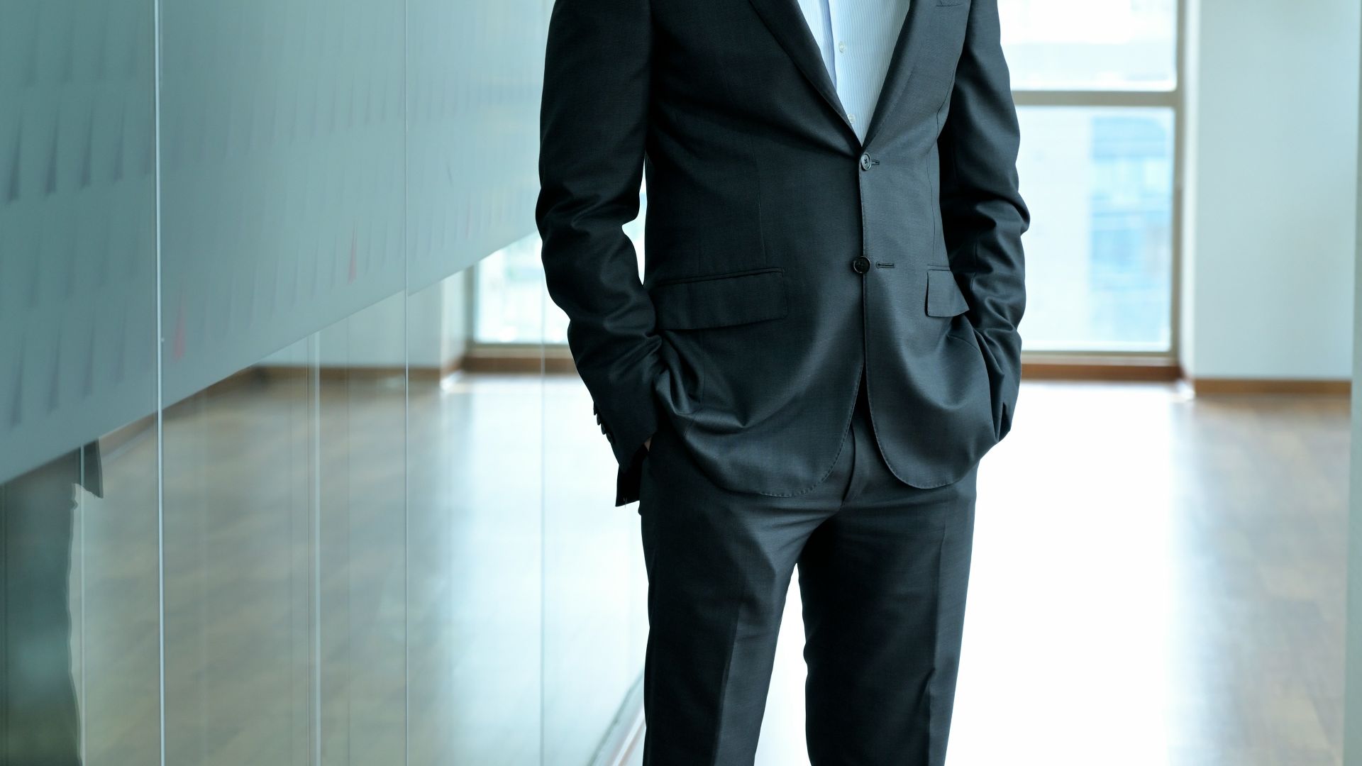 A man in a suit standing in an office hallway.