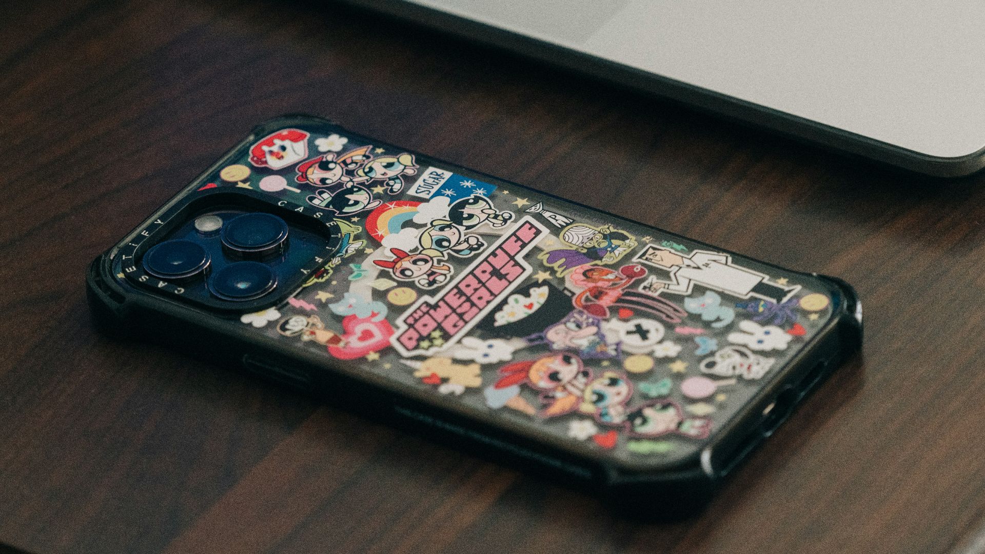 Phone with decorative case sits near a laptop.